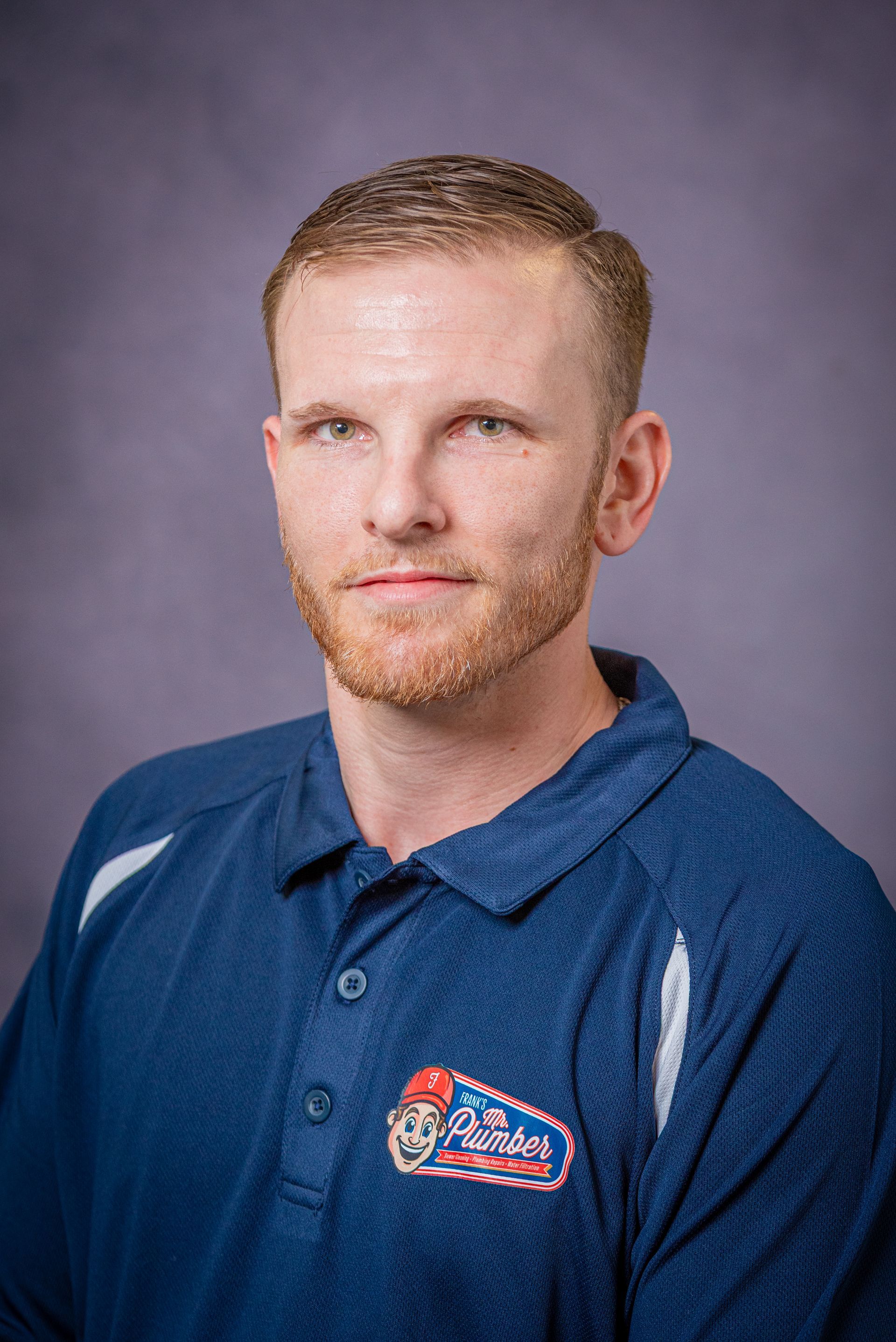 Man with short blond hair, wearing a blue polo shirt, looking at the camera.