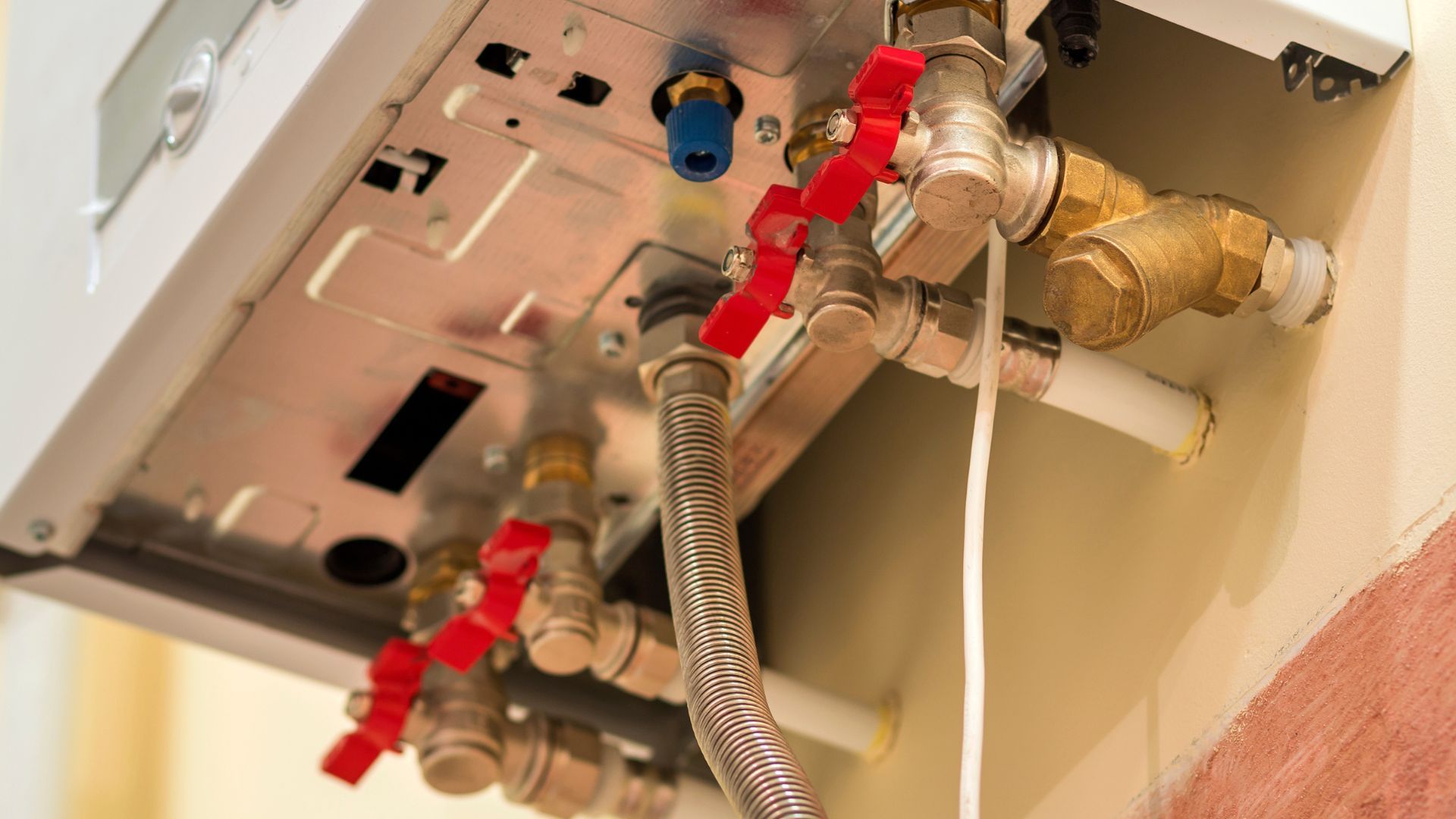Close-up of boiler system with pipes and valves, some with red lever handles.