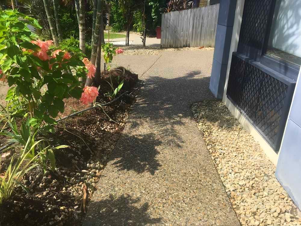 A Sidewalk Leading To A House With A Fence And Flowers — Tropical North Concreting In Trinity Park, QLD
