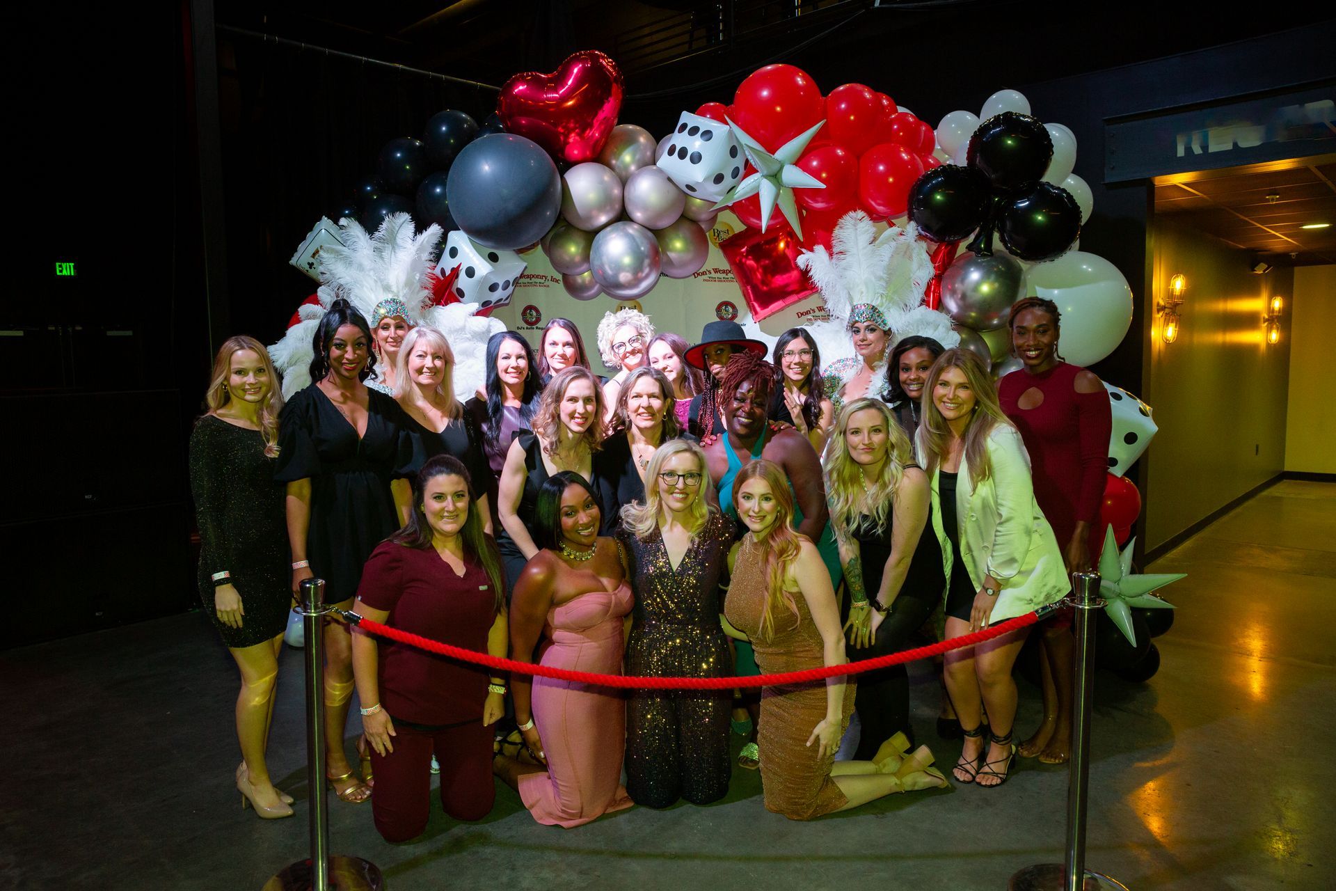 A group of women are posing for a picture in front of a wall of balloons.