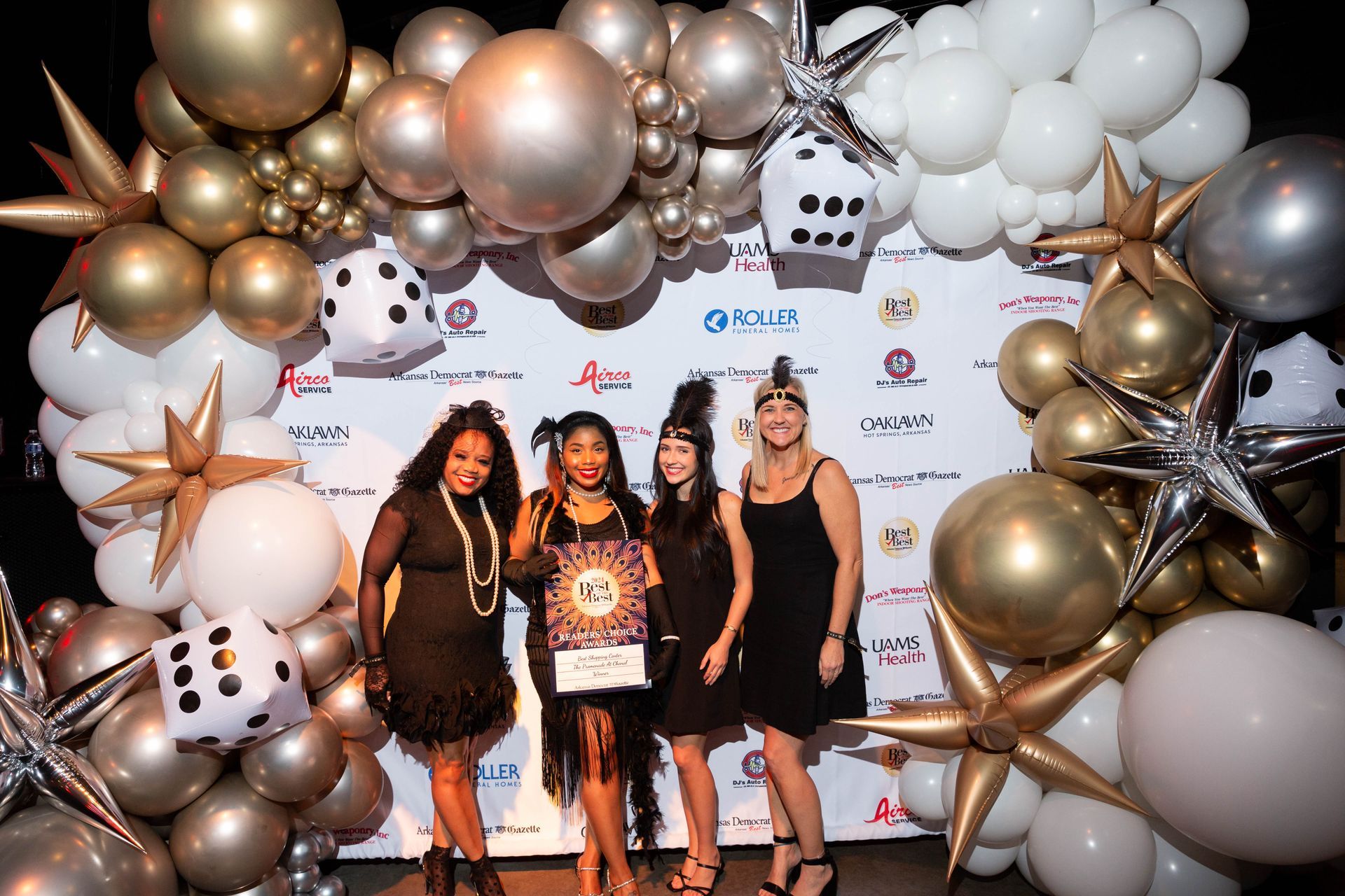 A group of women are standing in front of a wall of balloons.