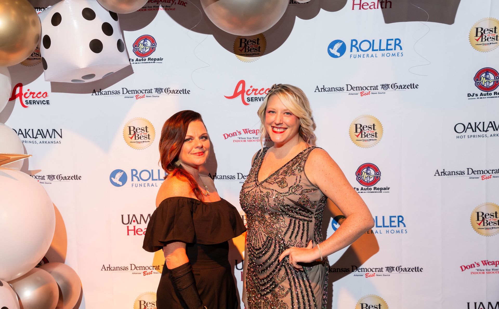 Two women are standing next to each other on a red carpet.