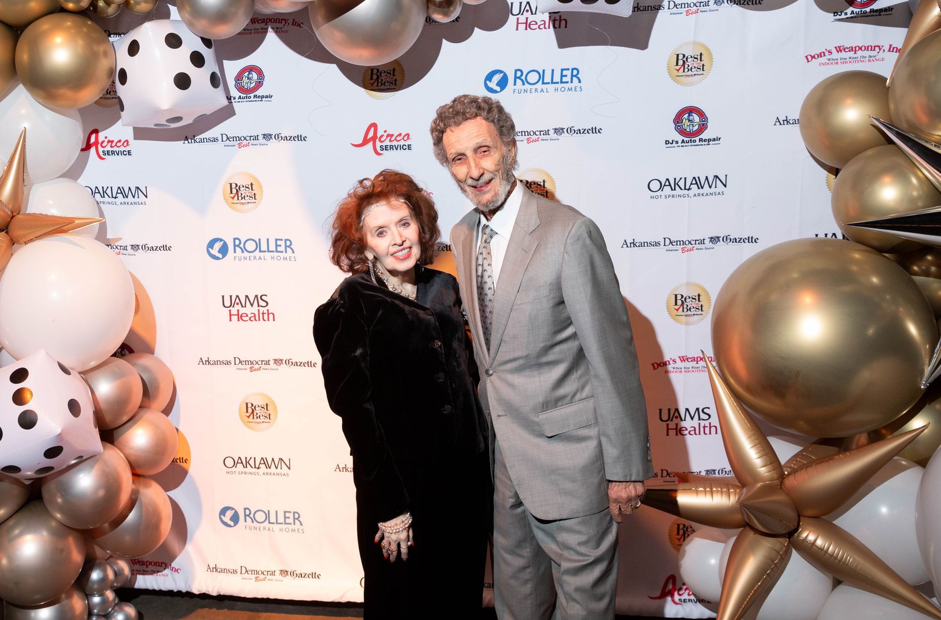 A man and a woman are posing for a picture in front of balloons.