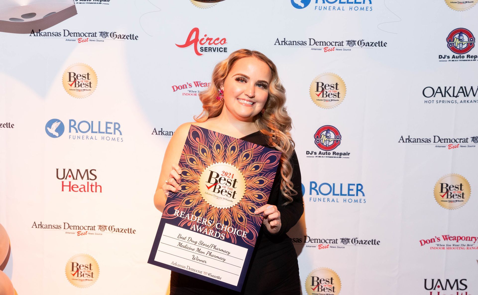 A woman is standing in front of a wall holding a plaque.