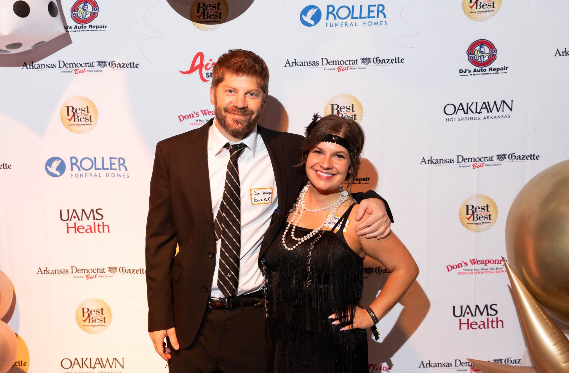 A man and a woman are posing for a picture on a red carpet.