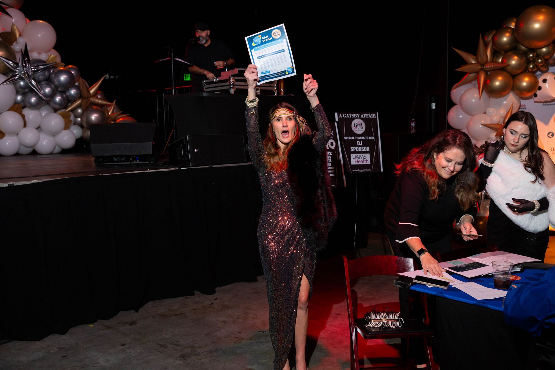 A woman in a dress is standing on a stage holding a certificate.