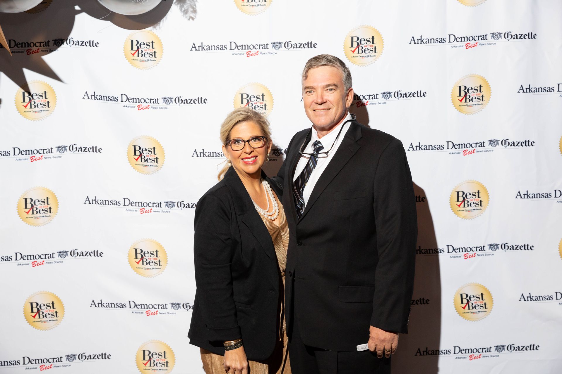 A man and a woman are posing for a picture on a red carpet.