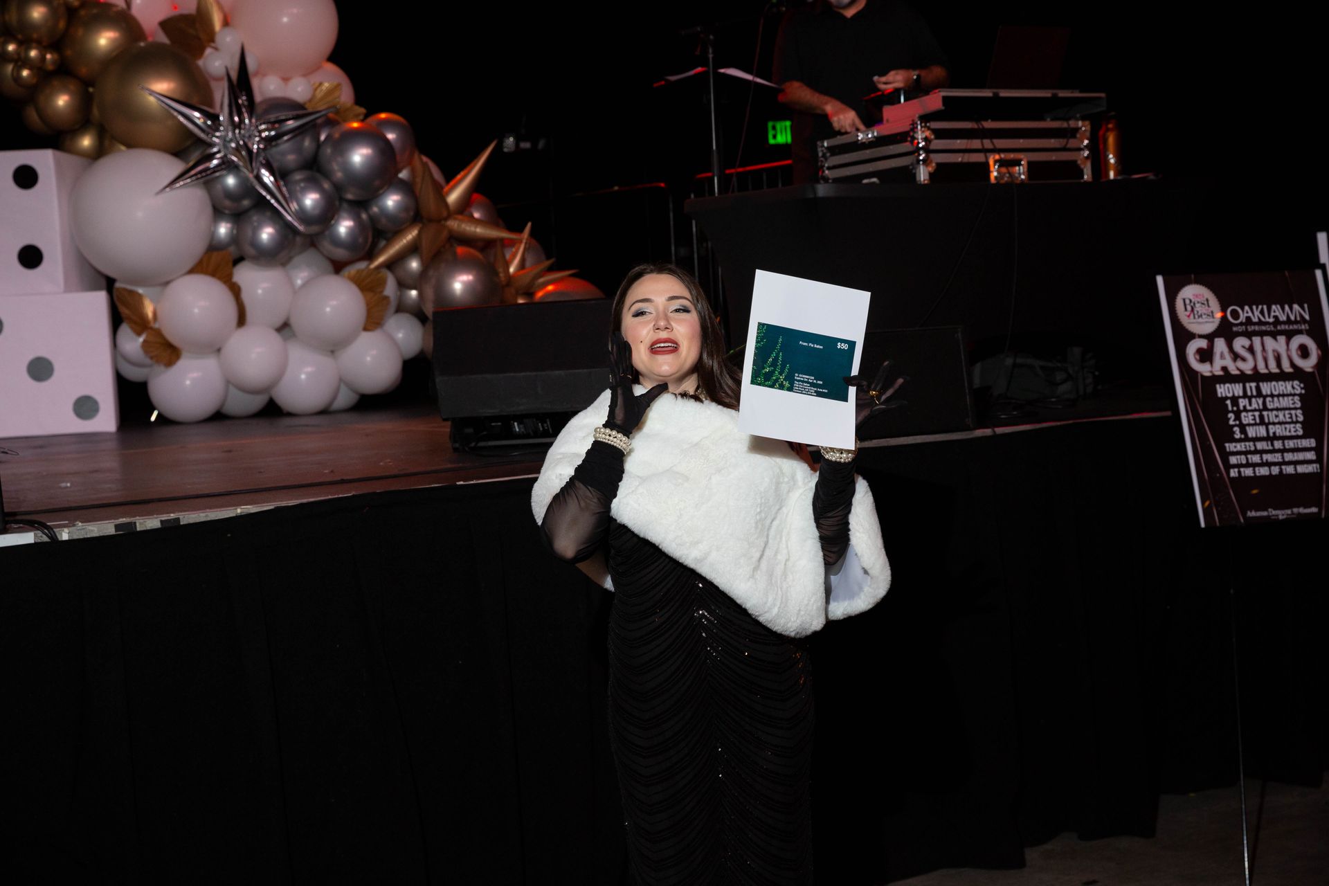 A woman is standing on a stage holding a piece of paper.