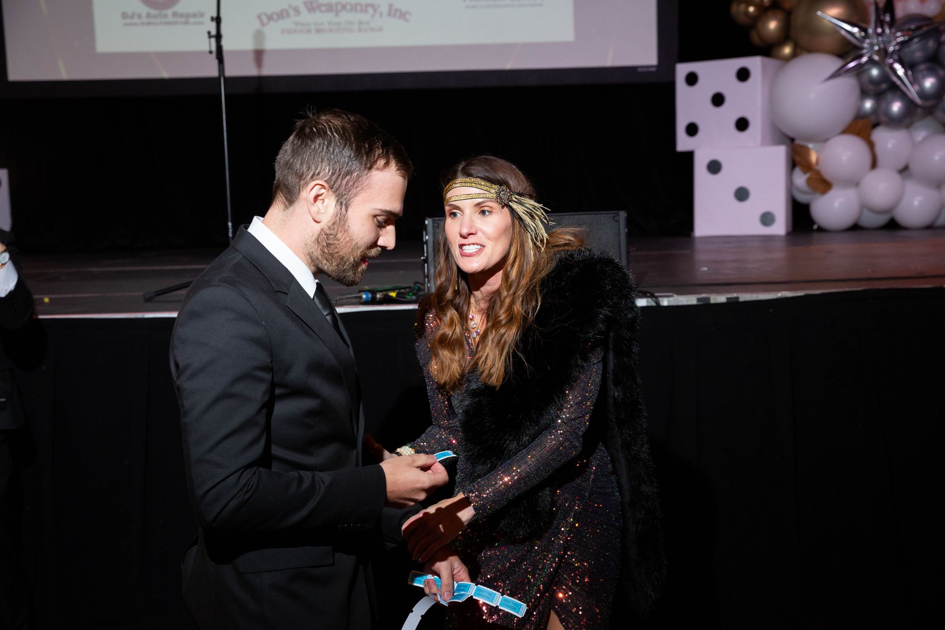 A man and a woman are standing on a stage holding hands.