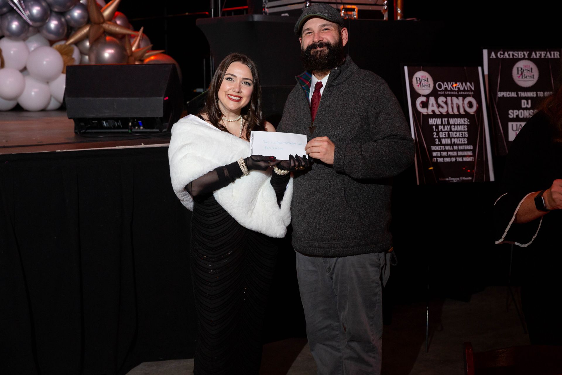 A man and a woman are standing next to each other holding a check.