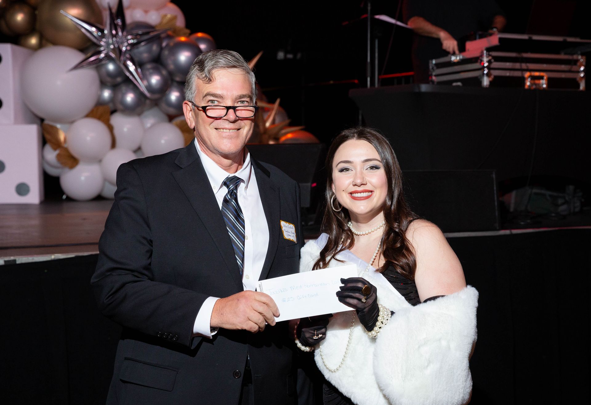 A man and a woman are standing next to each other on a stage holding a check.