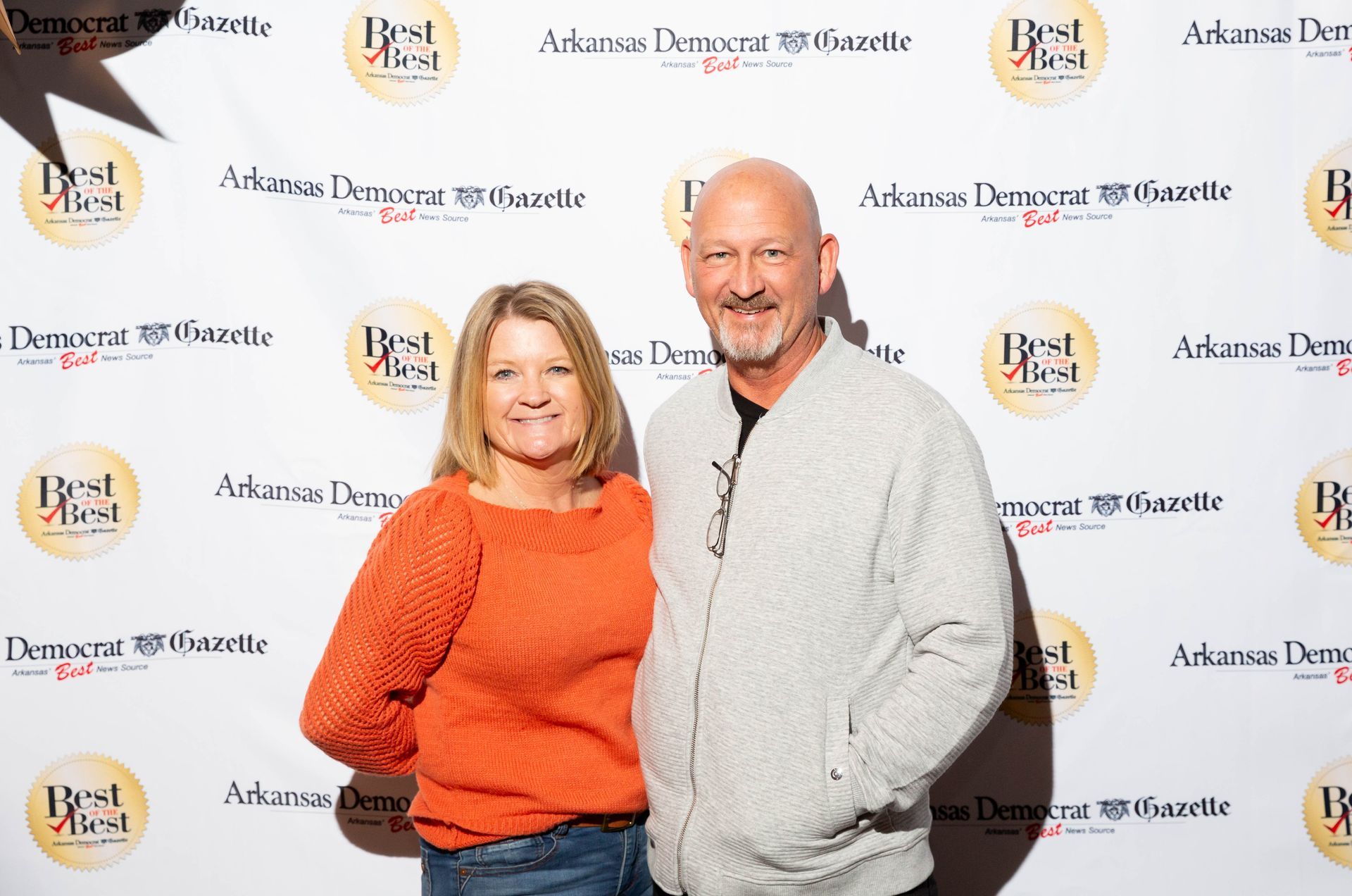 A man and a woman are posing for a picture in front of a wall.