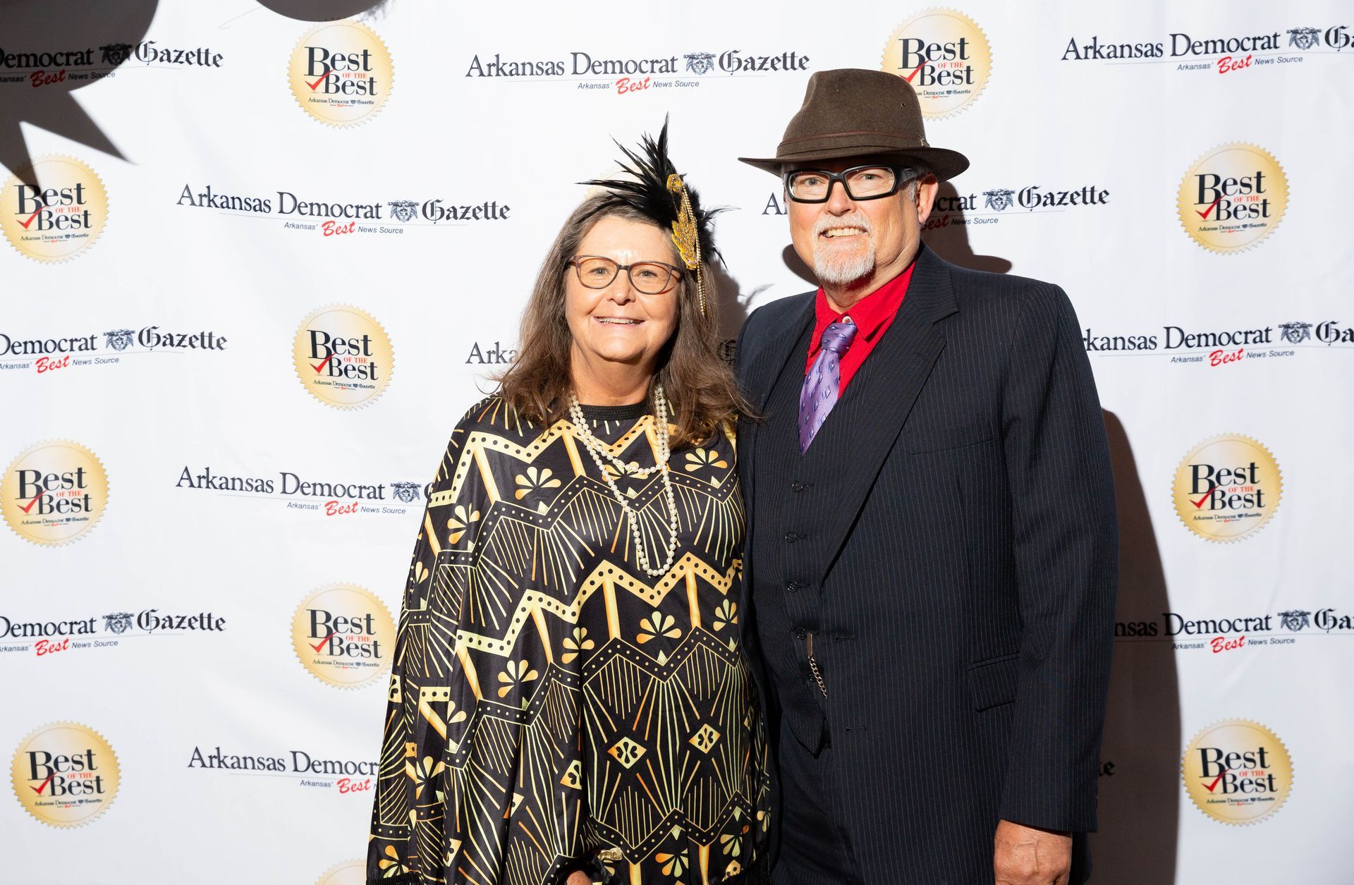A man and a woman are standing next to each other on a red carpet.