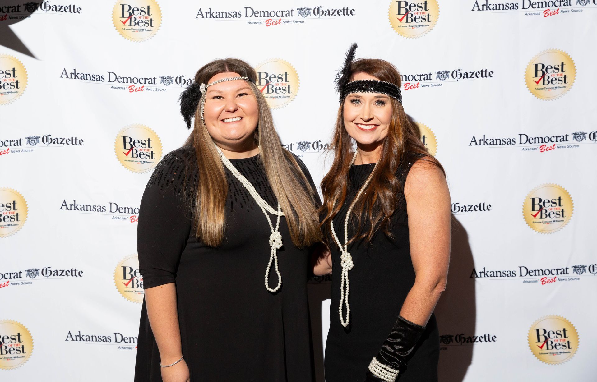 Two women are posing for a picture on a red carpet.