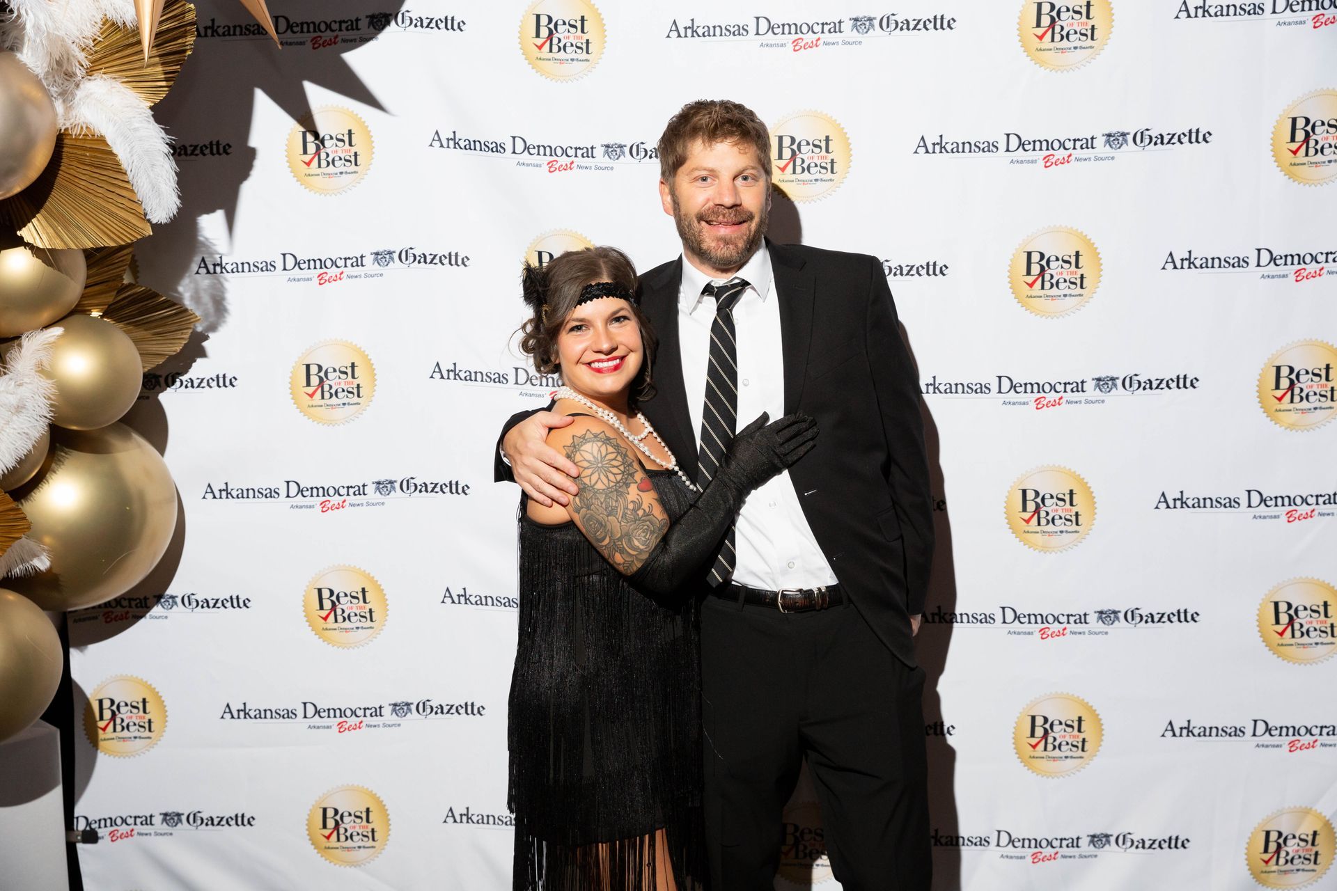 A man and a woman are posing for a picture on a red carpet.