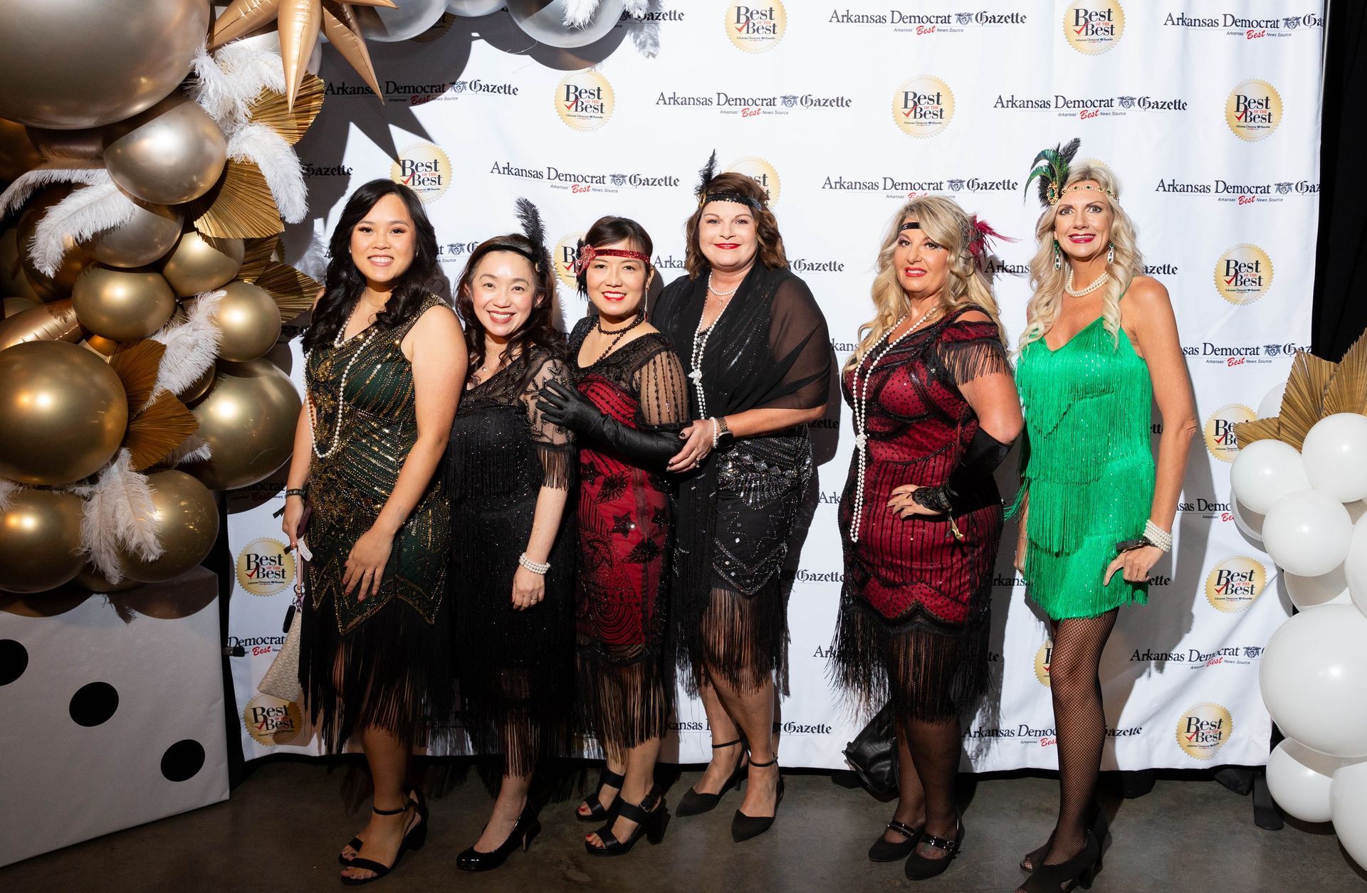 A group of women are posing for a picture in front of balloons.