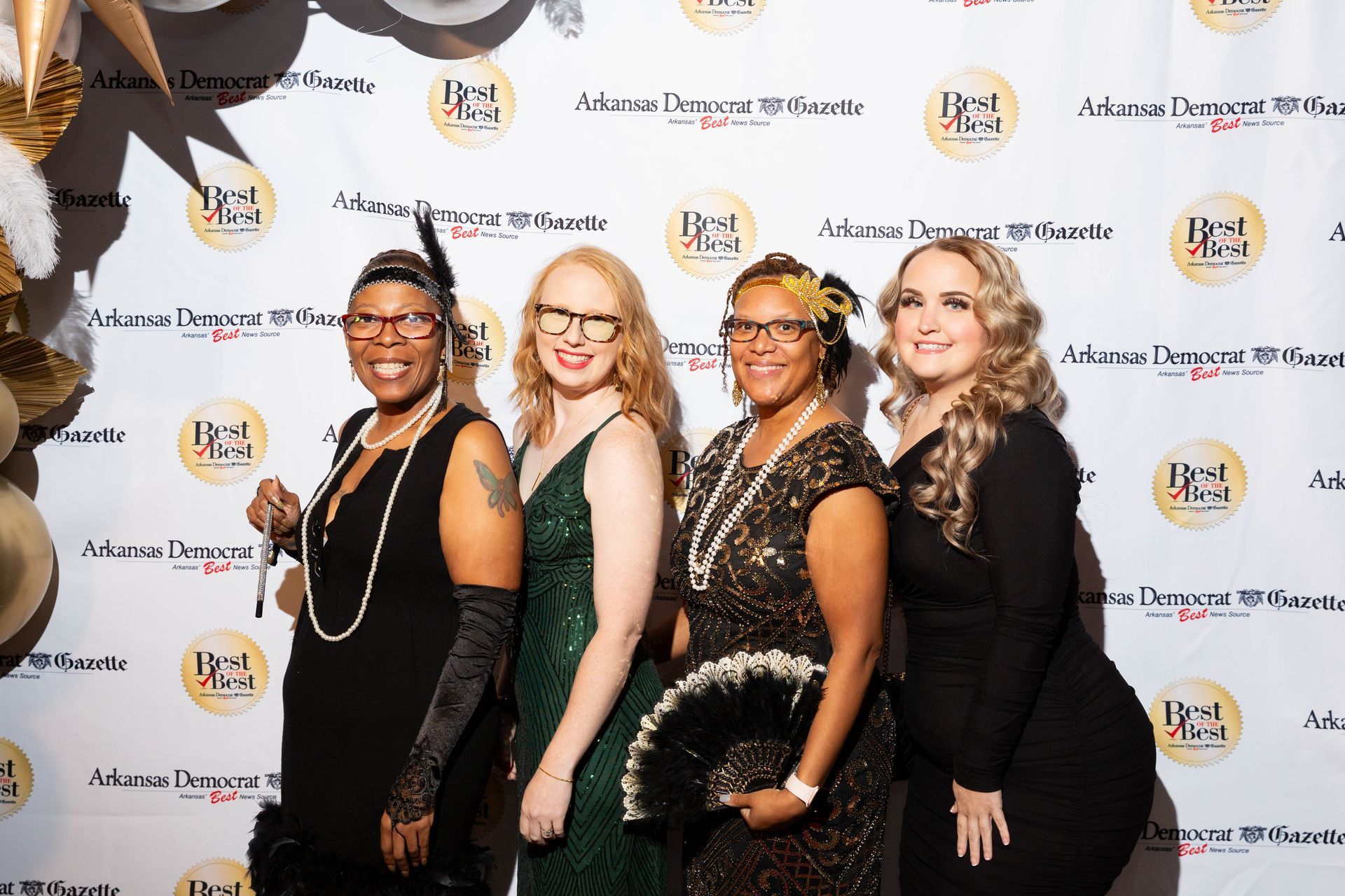 A group of women are posing for a picture in front of a red carpet.