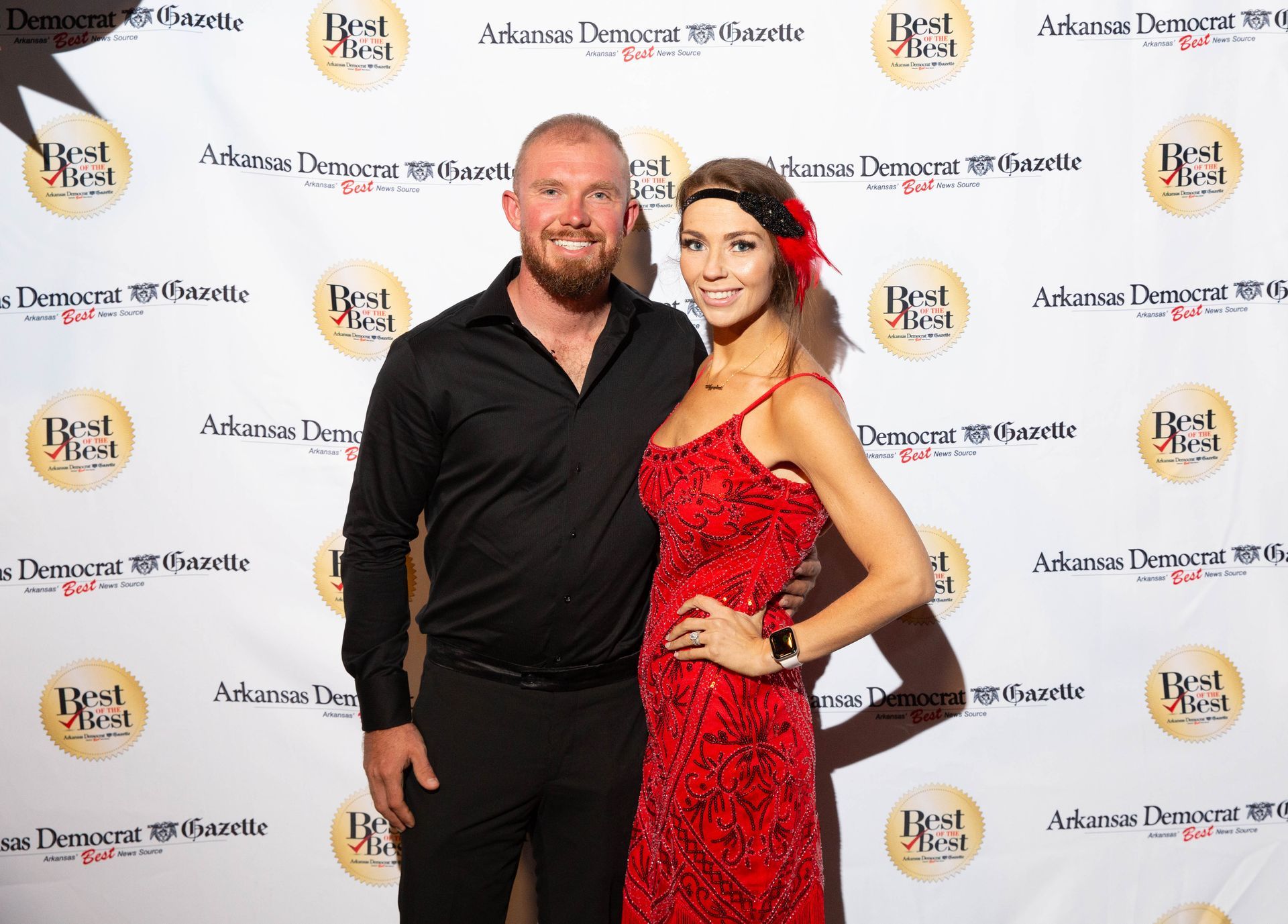 A man and a woman are posing for a picture on a red carpet.