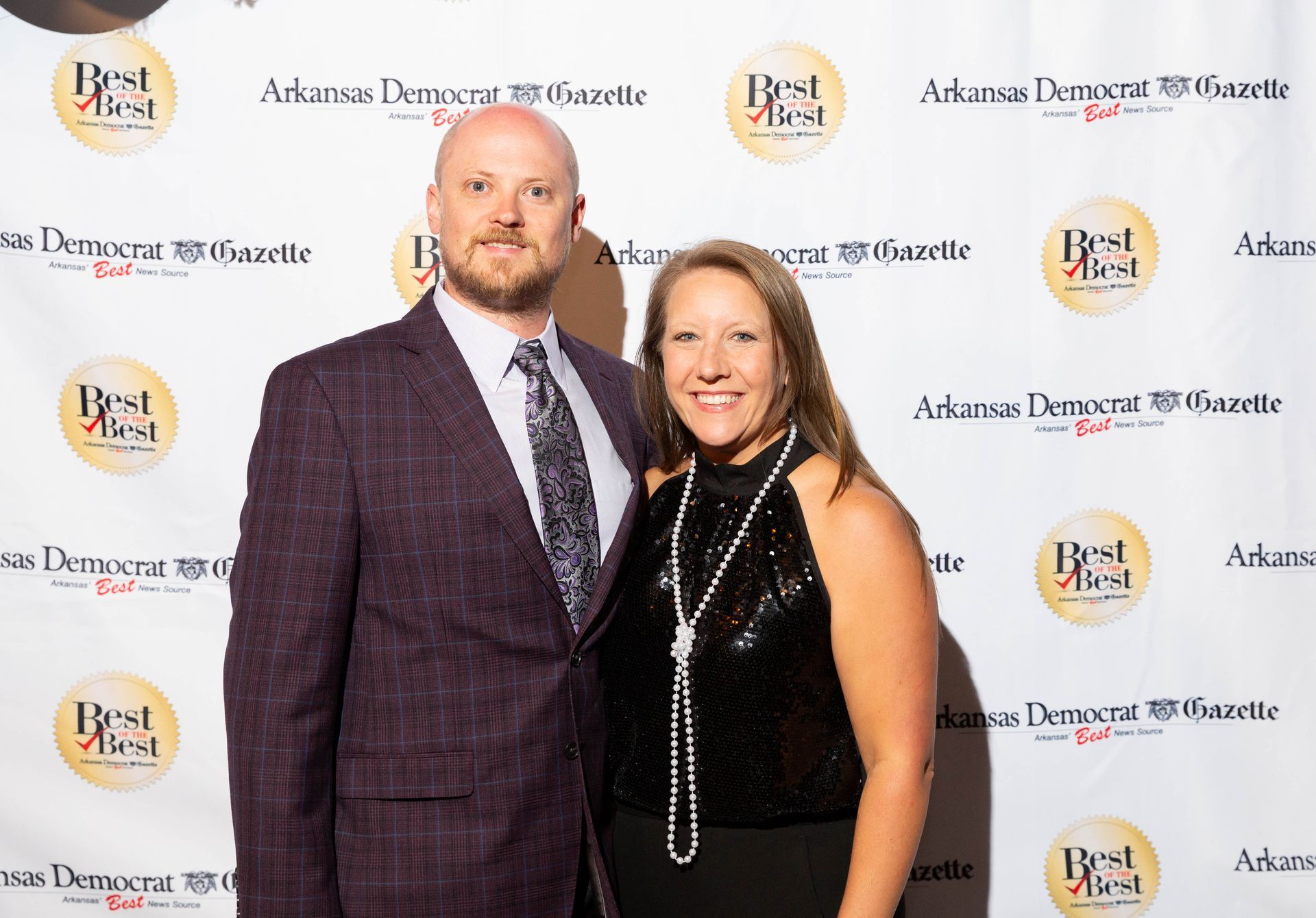 A man and a woman are posing for a picture on a red carpet.
