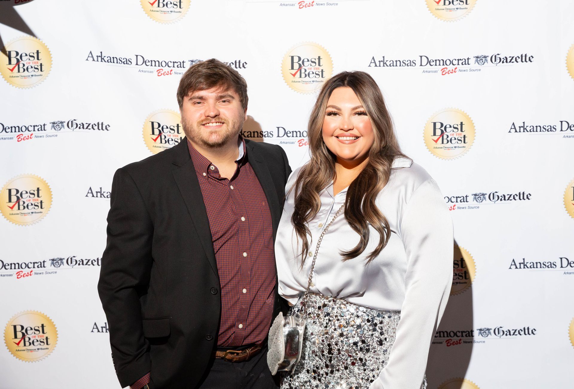 A man and a woman are posing for a picture on a red carpet.
