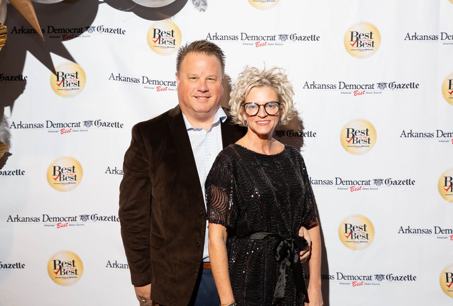 A man and a woman are posing for a picture on a red carpet.