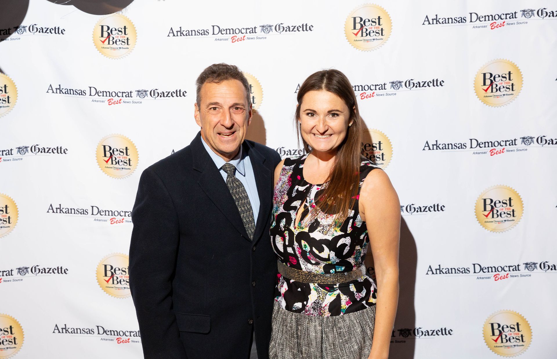 A man and a woman are posing for a picture on a red carpet.