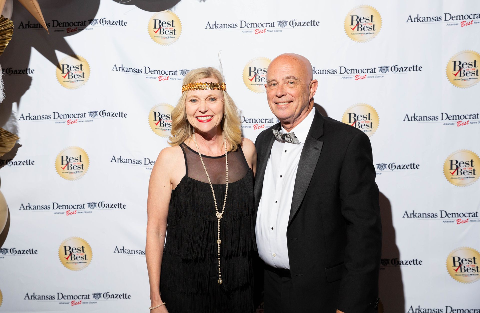 A man and a woman are posing for a picture on a red carpet.