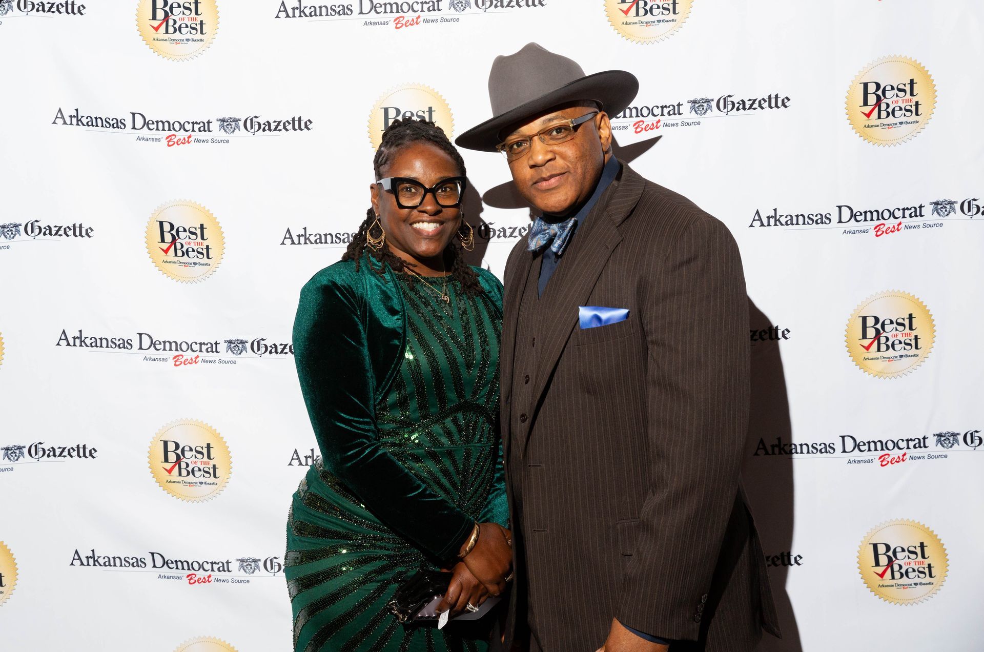 A man and a woman are posing for a picture on a red carpet.