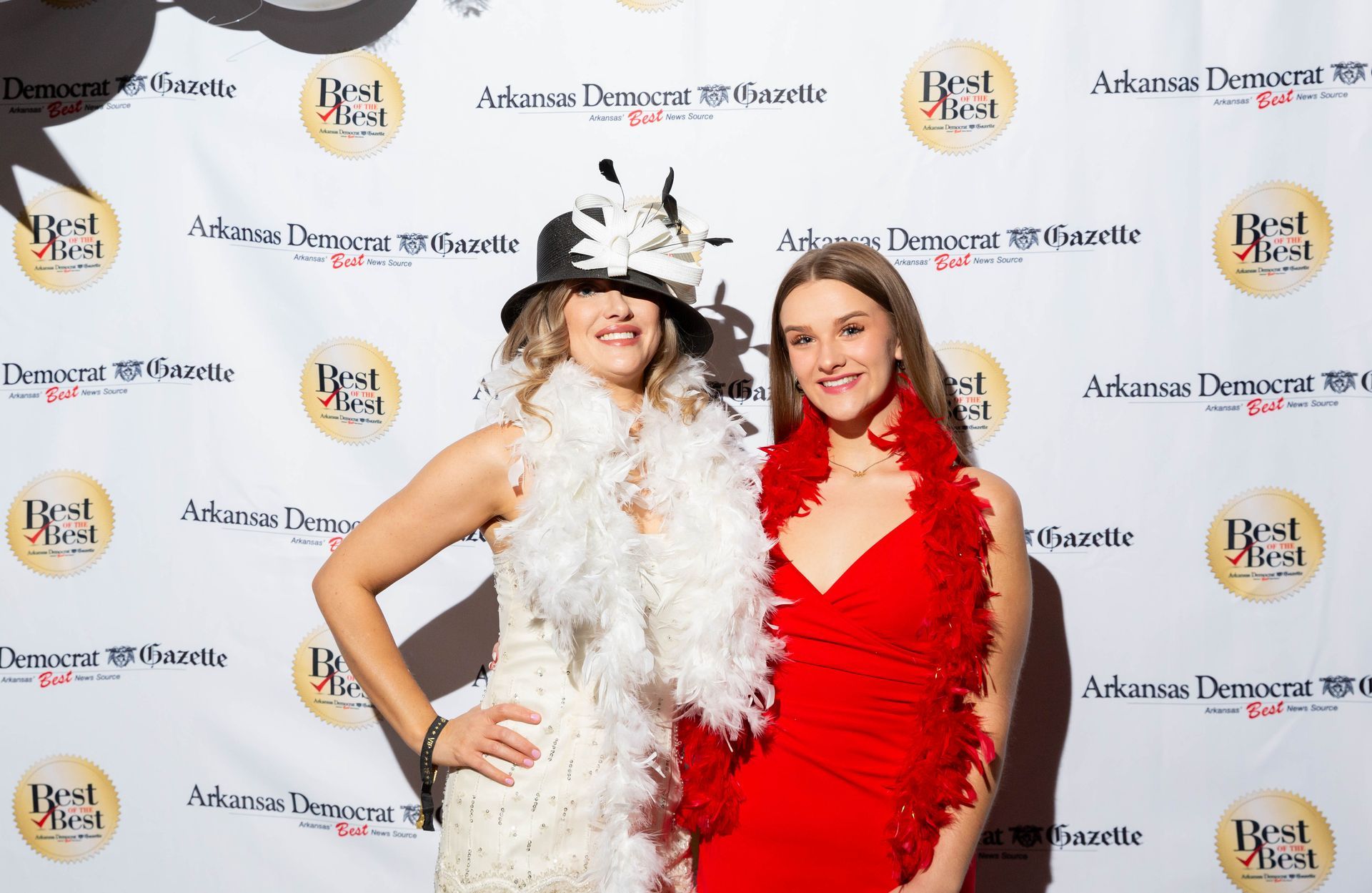 Two women are posing for a picture on a red carpet.