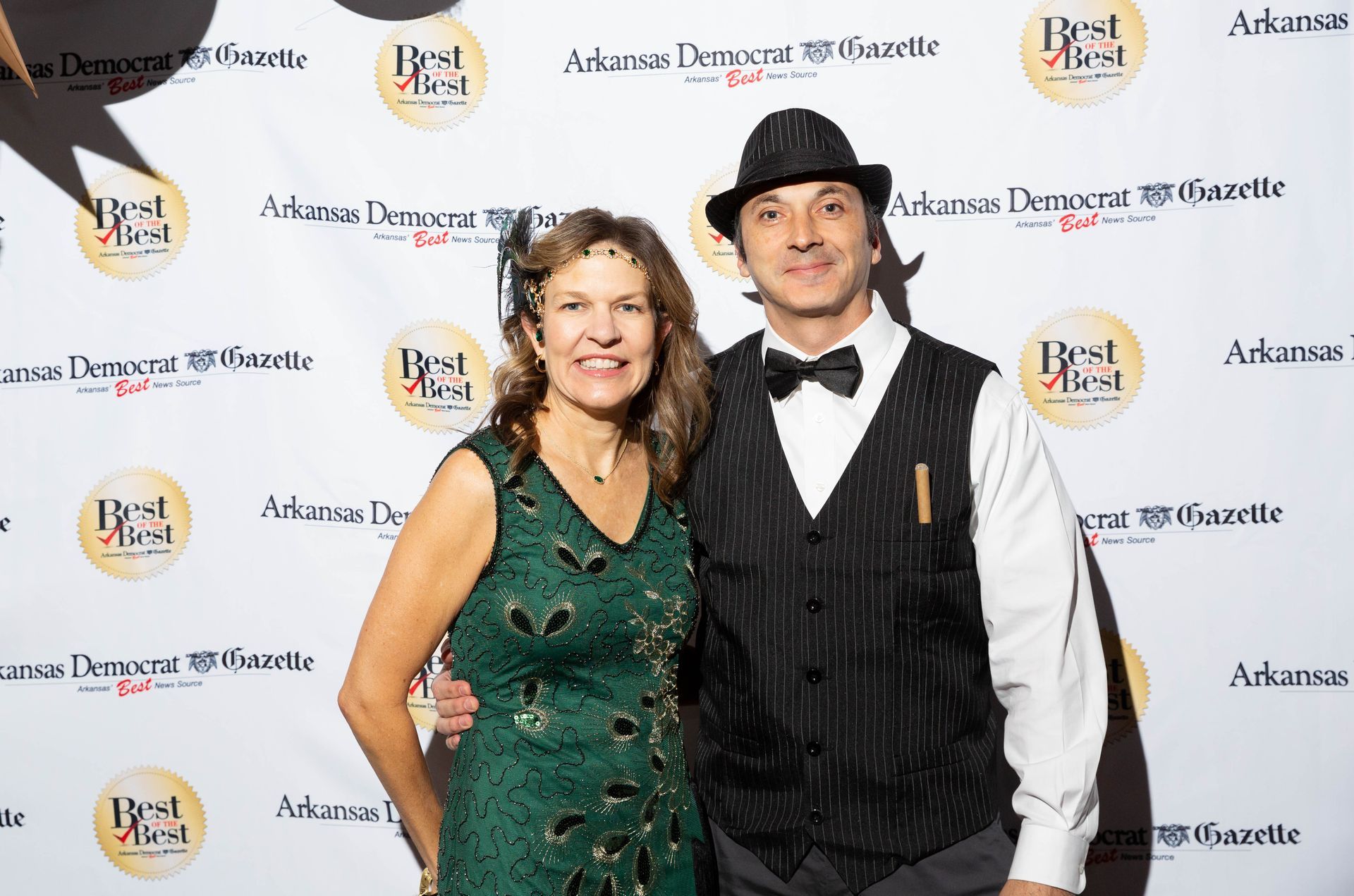 A man and a woman are posing for a picture on a red carpet.