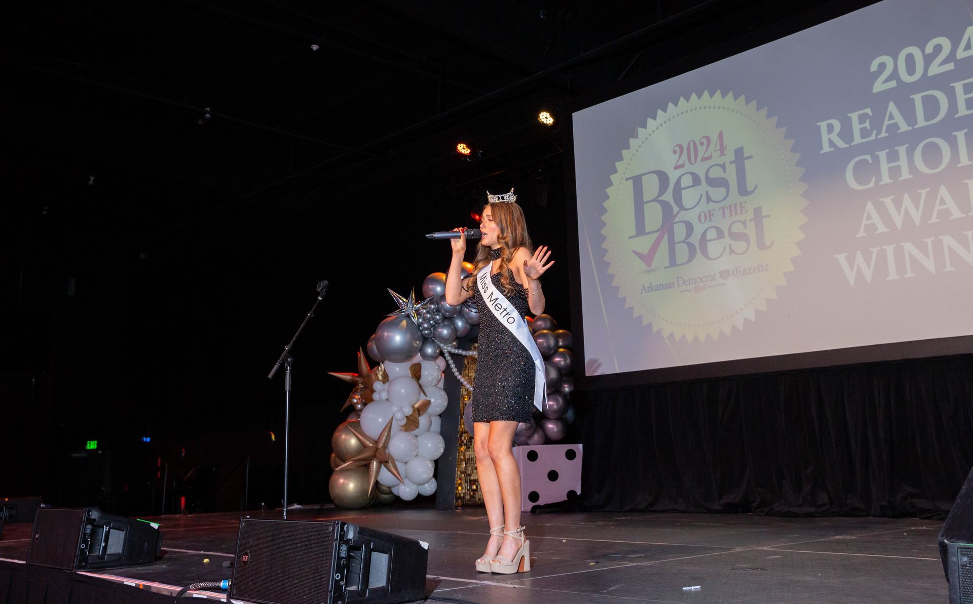 A woman is standing on a stage singing into a microphone.