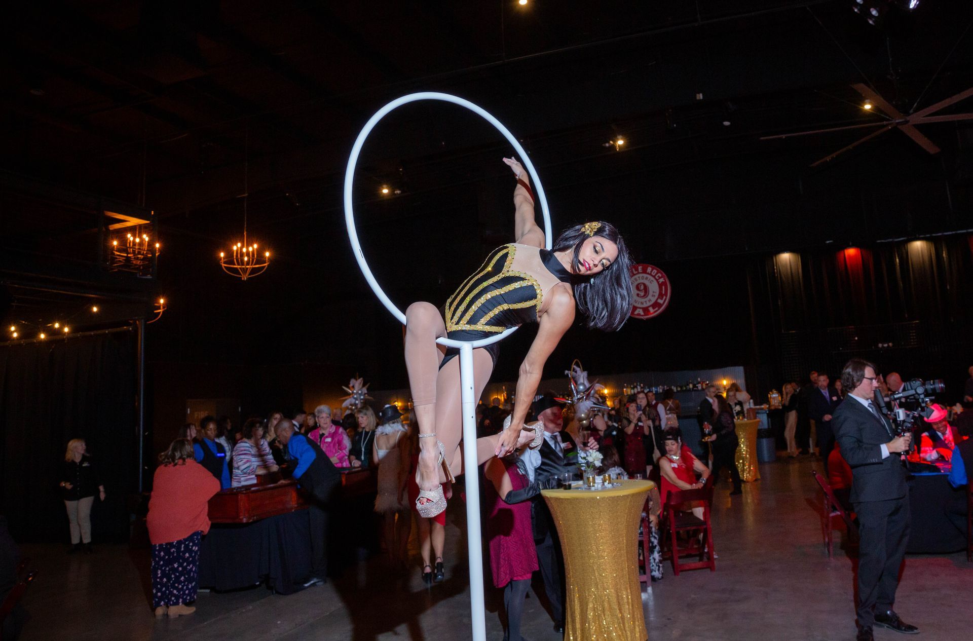 A woman is doing aerial acrobatics in an aerial hoop in front of a crowd.
