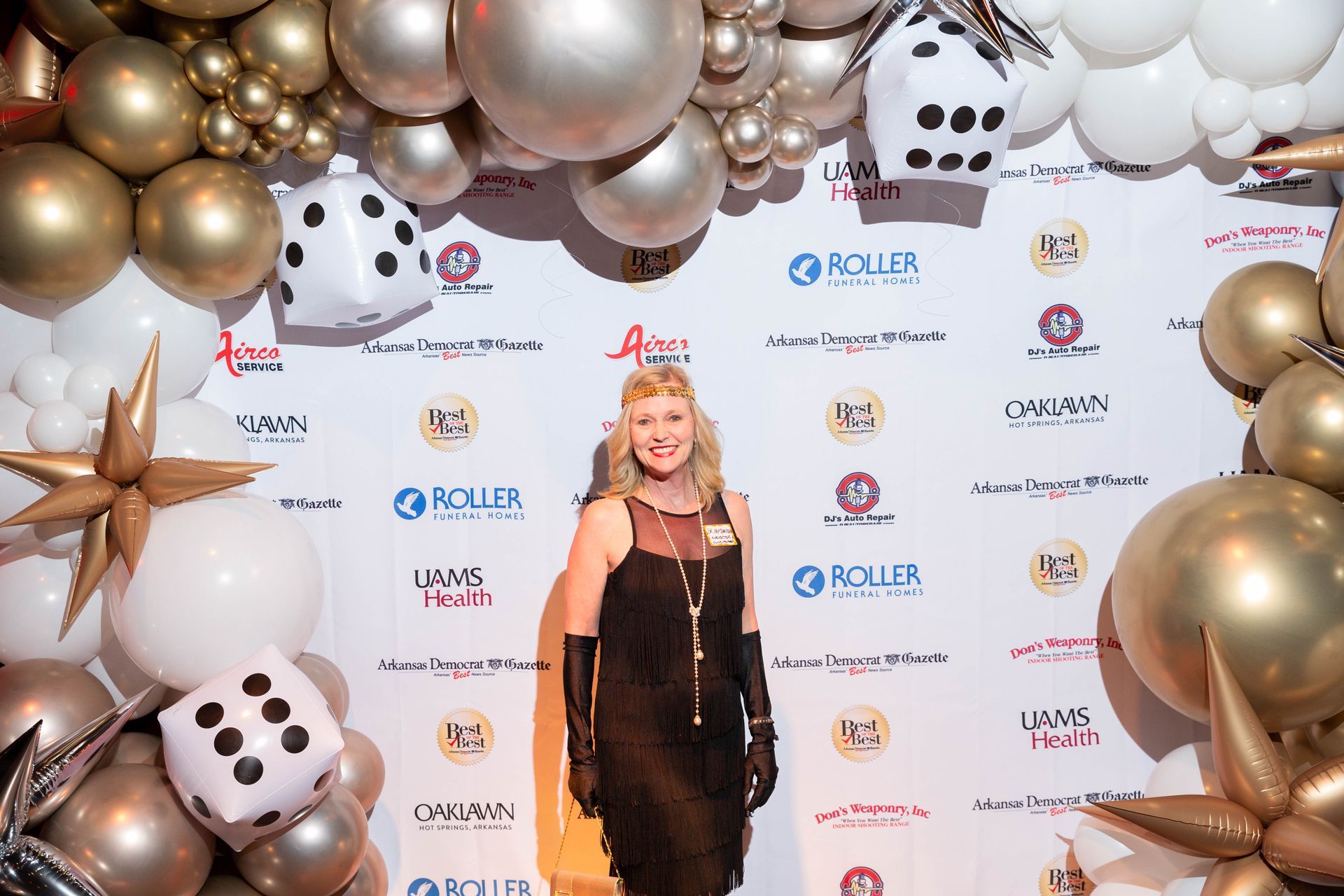 A woman is standing in front of a wall of balloons and dice.