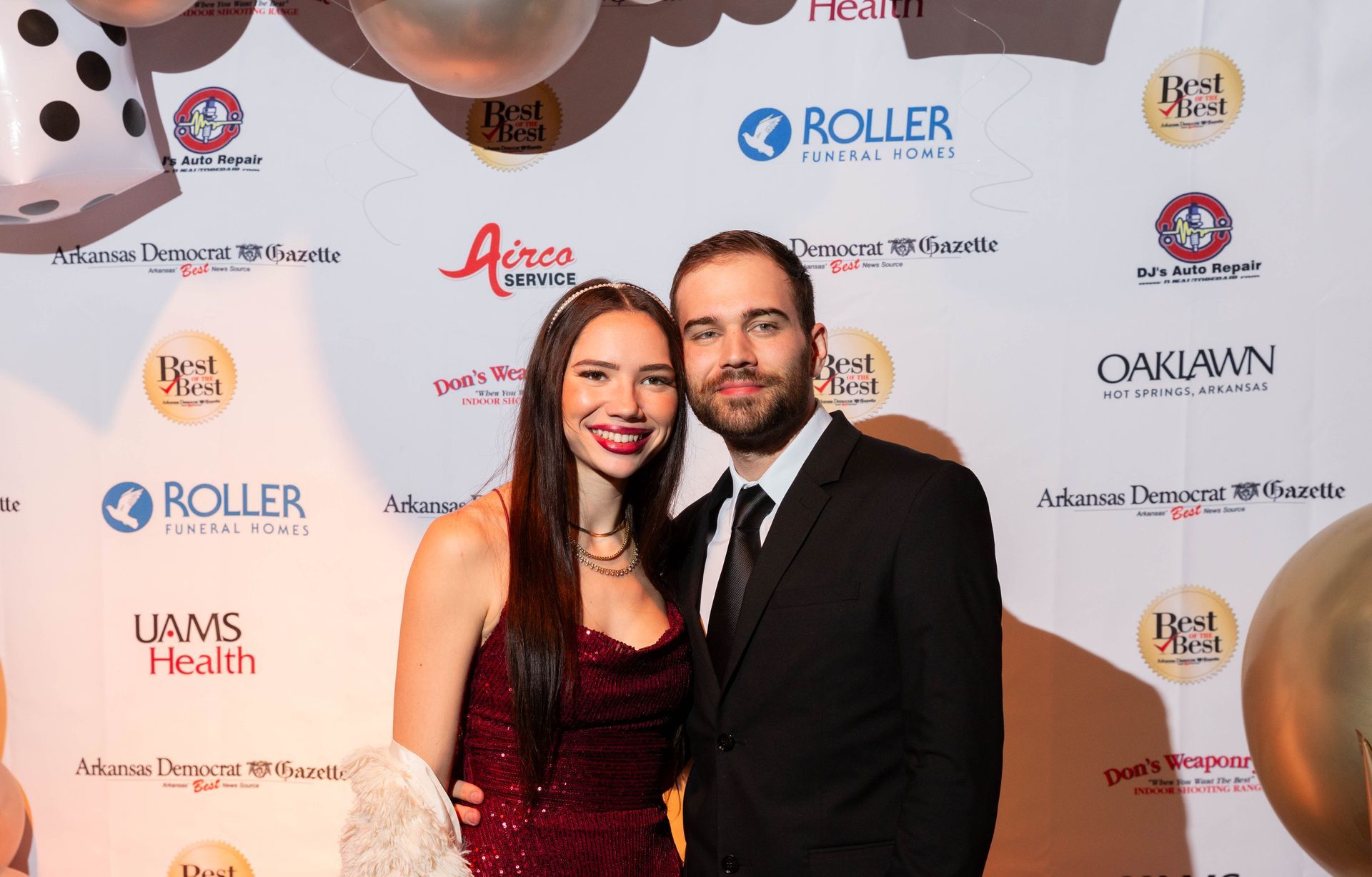 A man and a woman are posing for a picture on a red carpet.