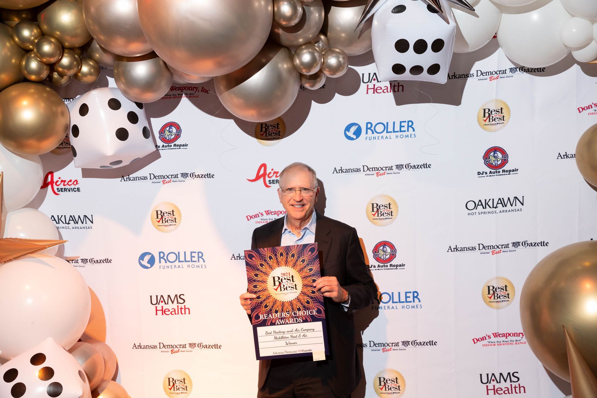 A man is holding a sign in front of a wall of balloons.