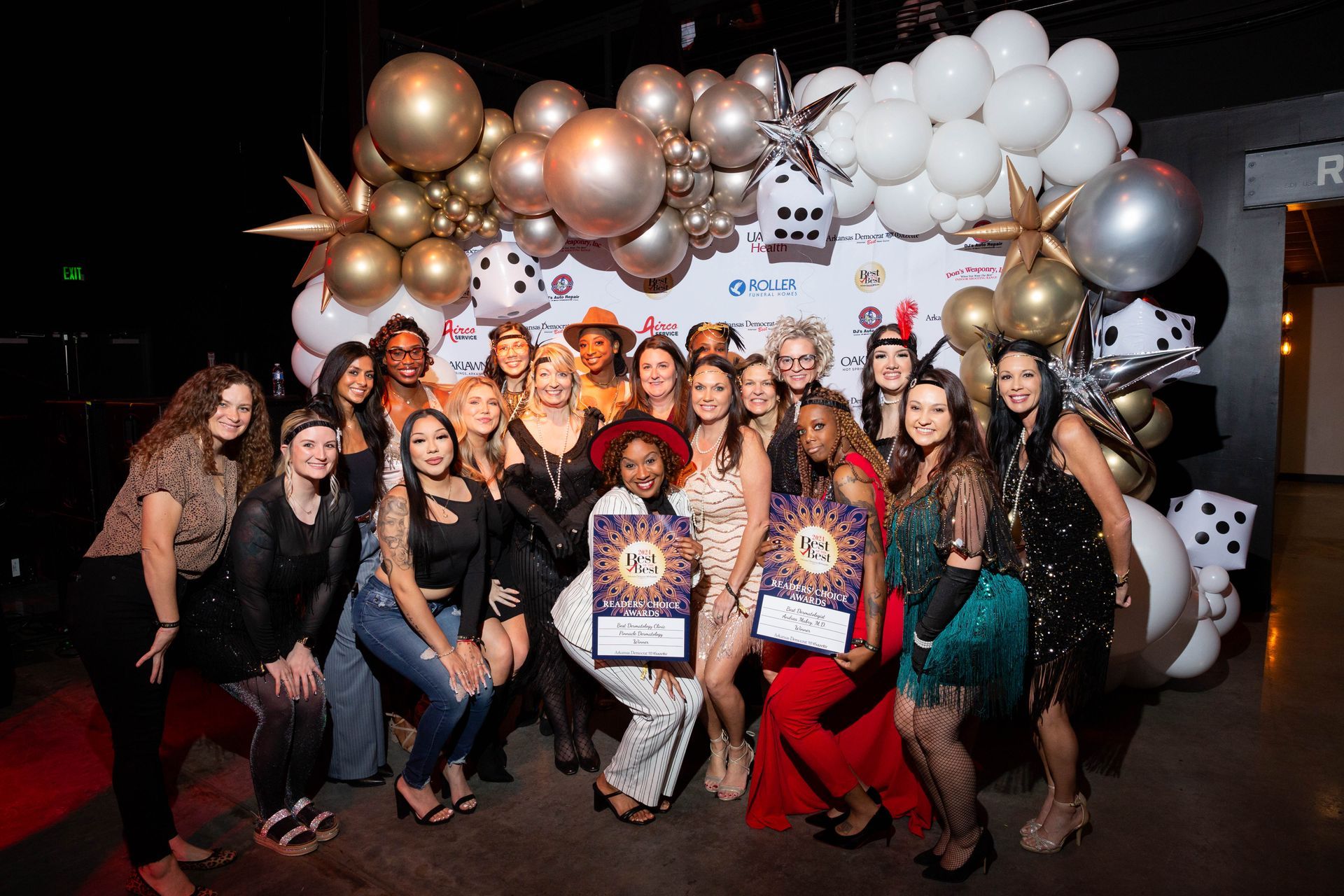 A group of women are posing for a picture in front of balloons.