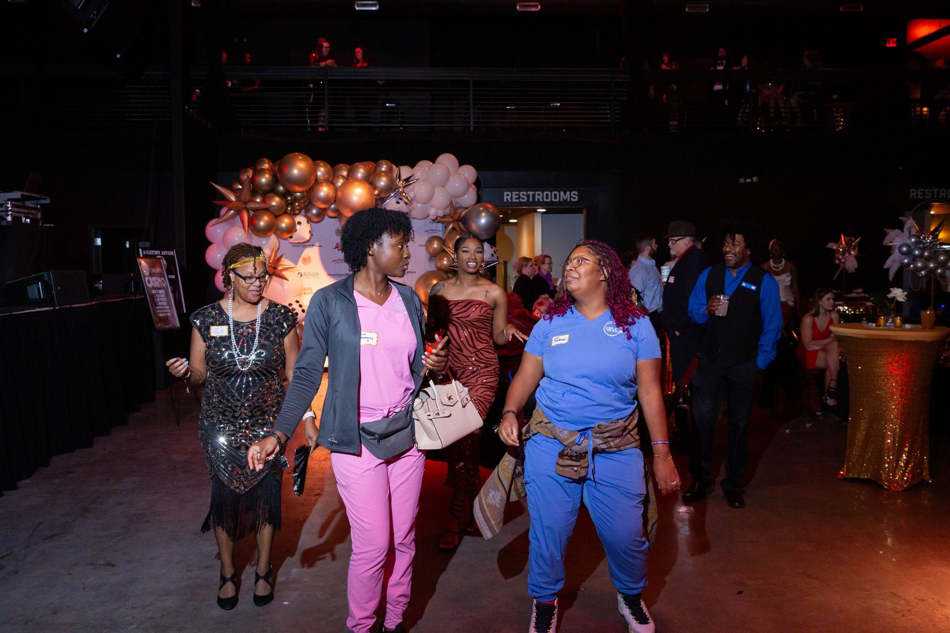 A group of women are walking down a hallway holding hands.
