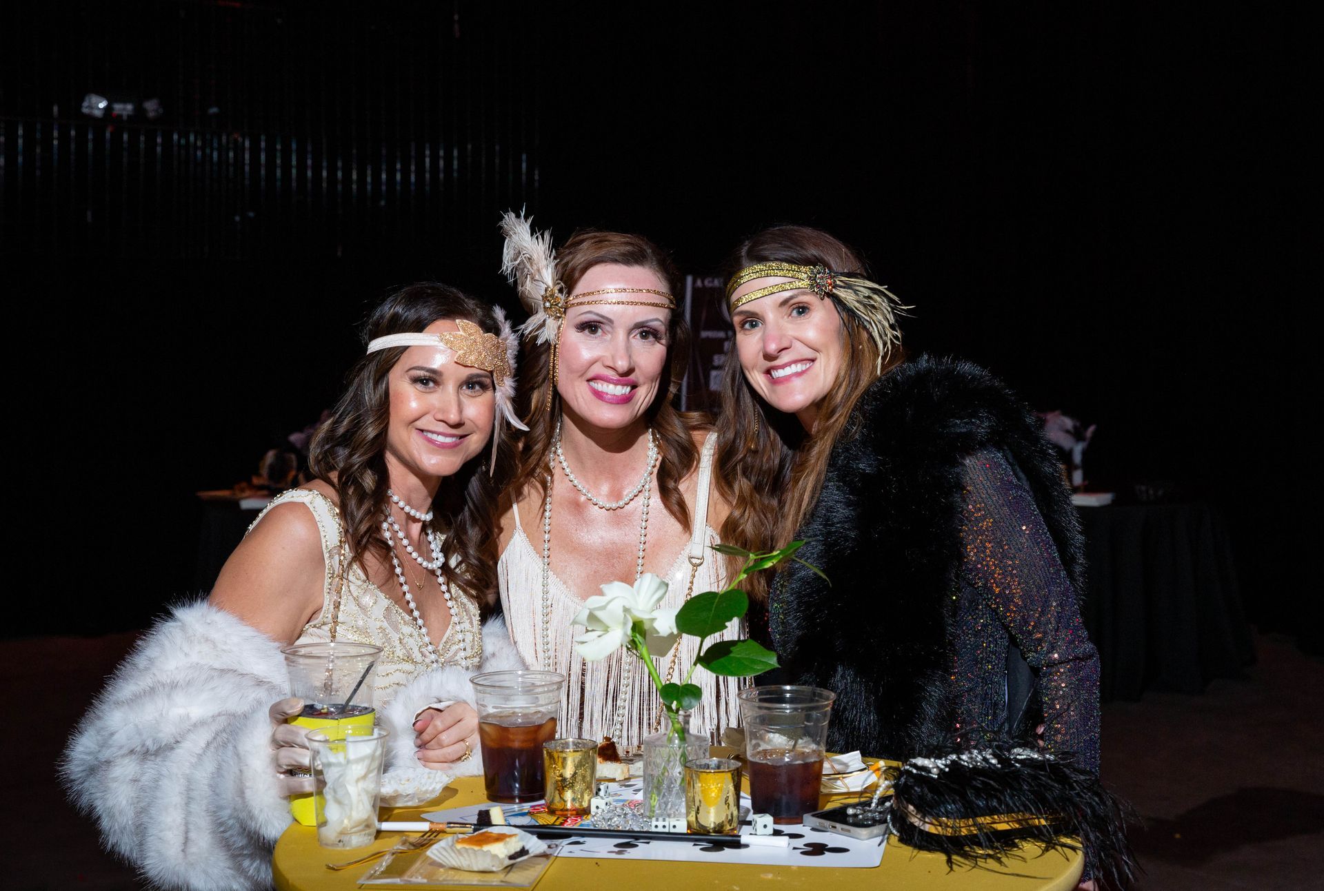 Three women are posing for a picture at a table at a party.