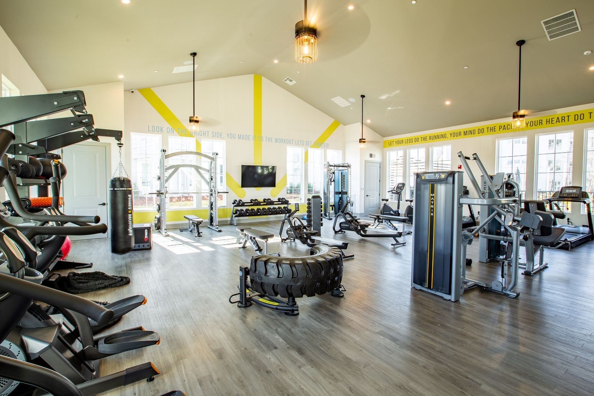 Modern gym interior with exercise machines, weight benches, and bright yellow accents.