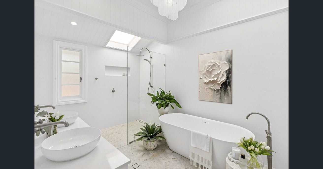 White bathroom with a freestanding tub, glass shower, and skylight. — Caprice Cabinets in Brisbine, QLD