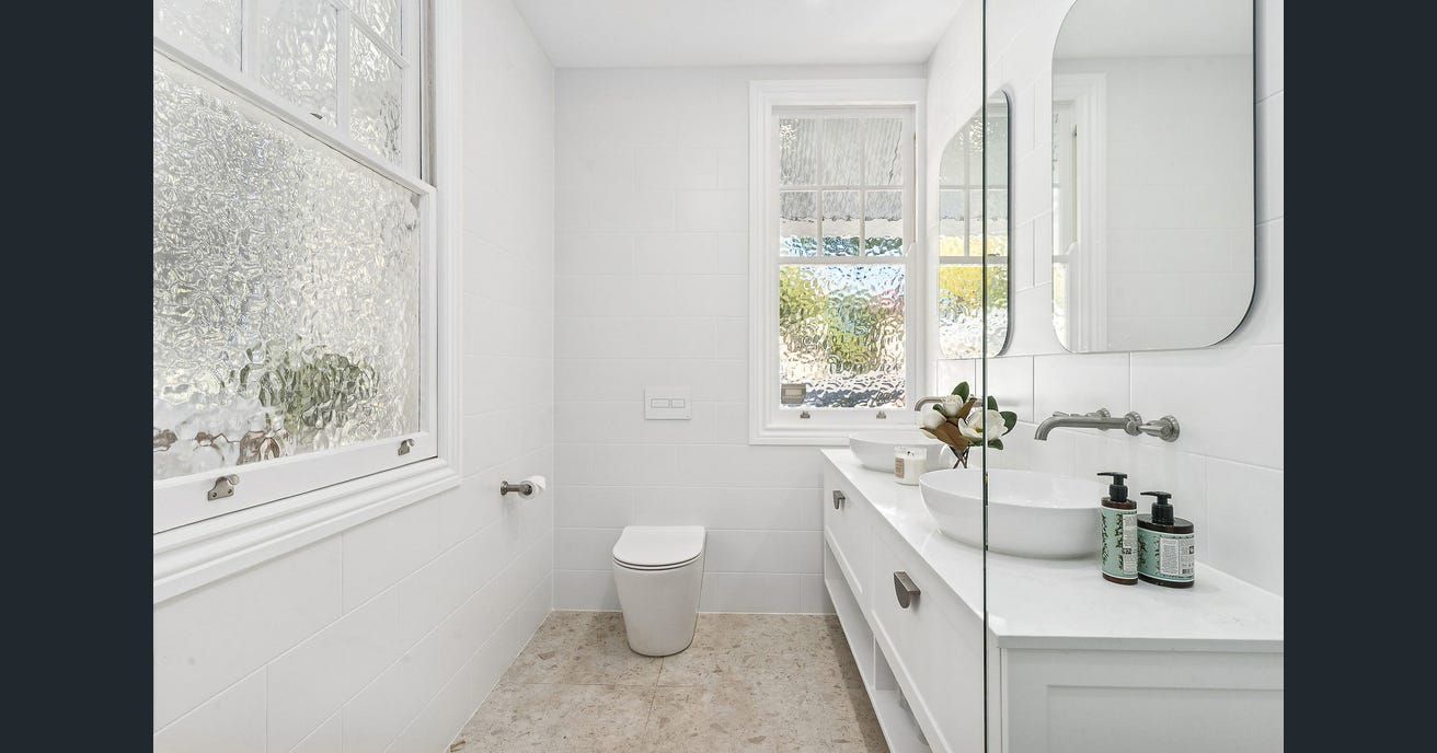 Modern laundry room with white cabinets, gray backsplash, and black appliances. — Caprice Cabinets in Coolum Beach, QLD