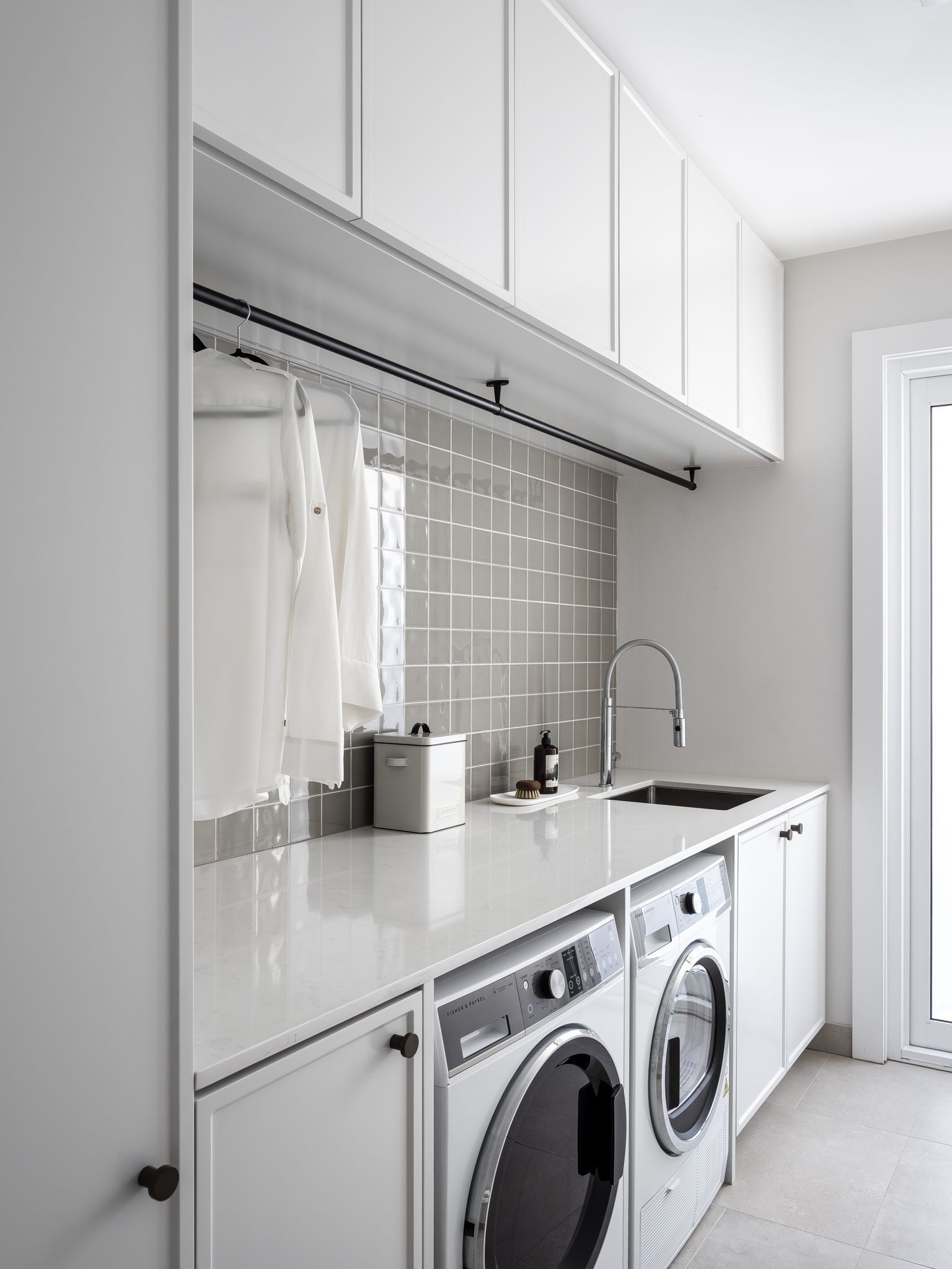 Modern laundry room with white cabinets, a washing machine, and a drying rack. — Caprice Cabinets in Noosa, QLD