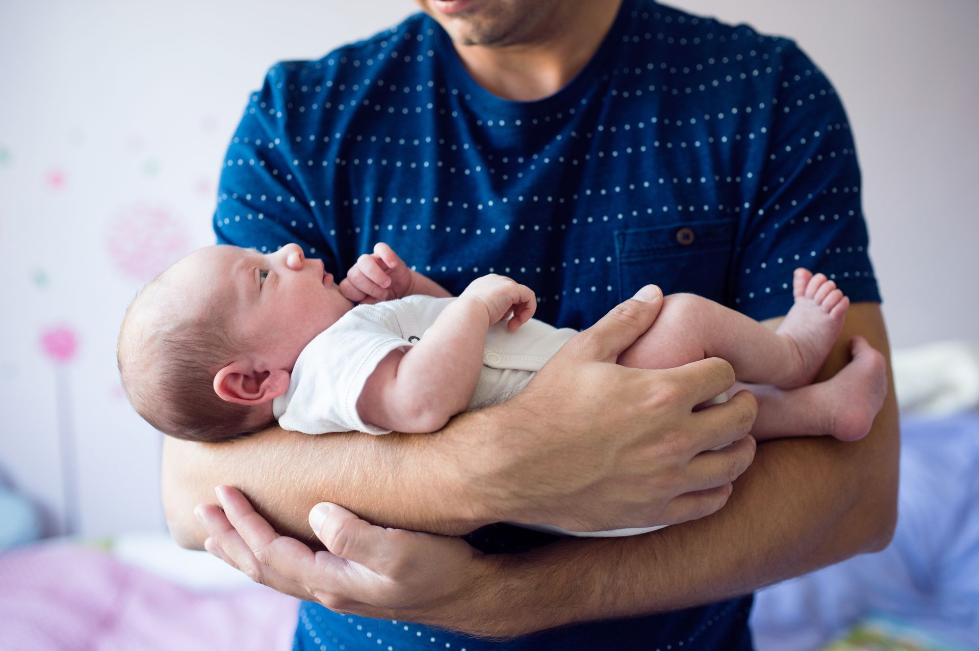 A man is holding a newborn baby in his arms.