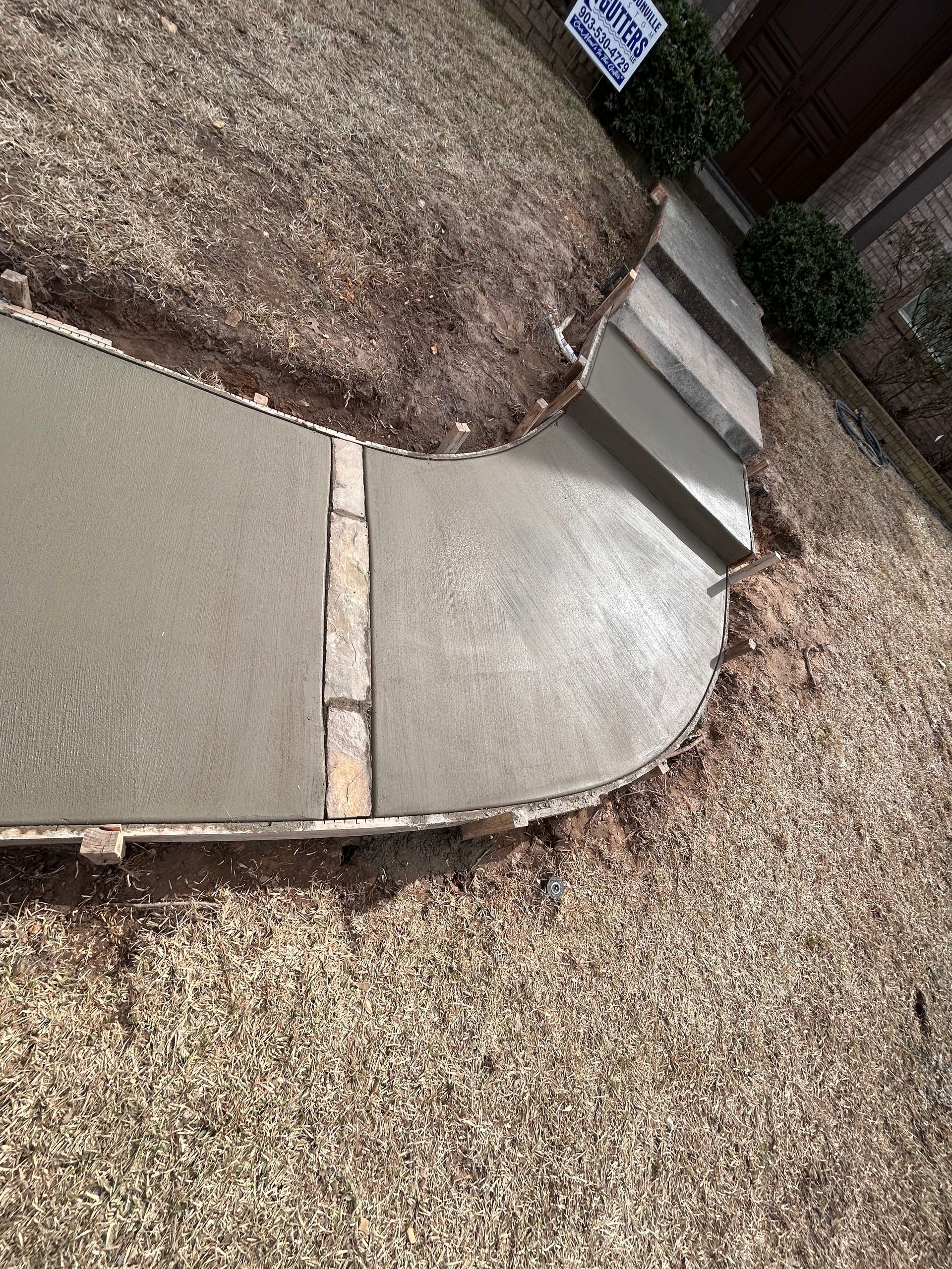 A concrete walkway is being built next to a gravel driveway.