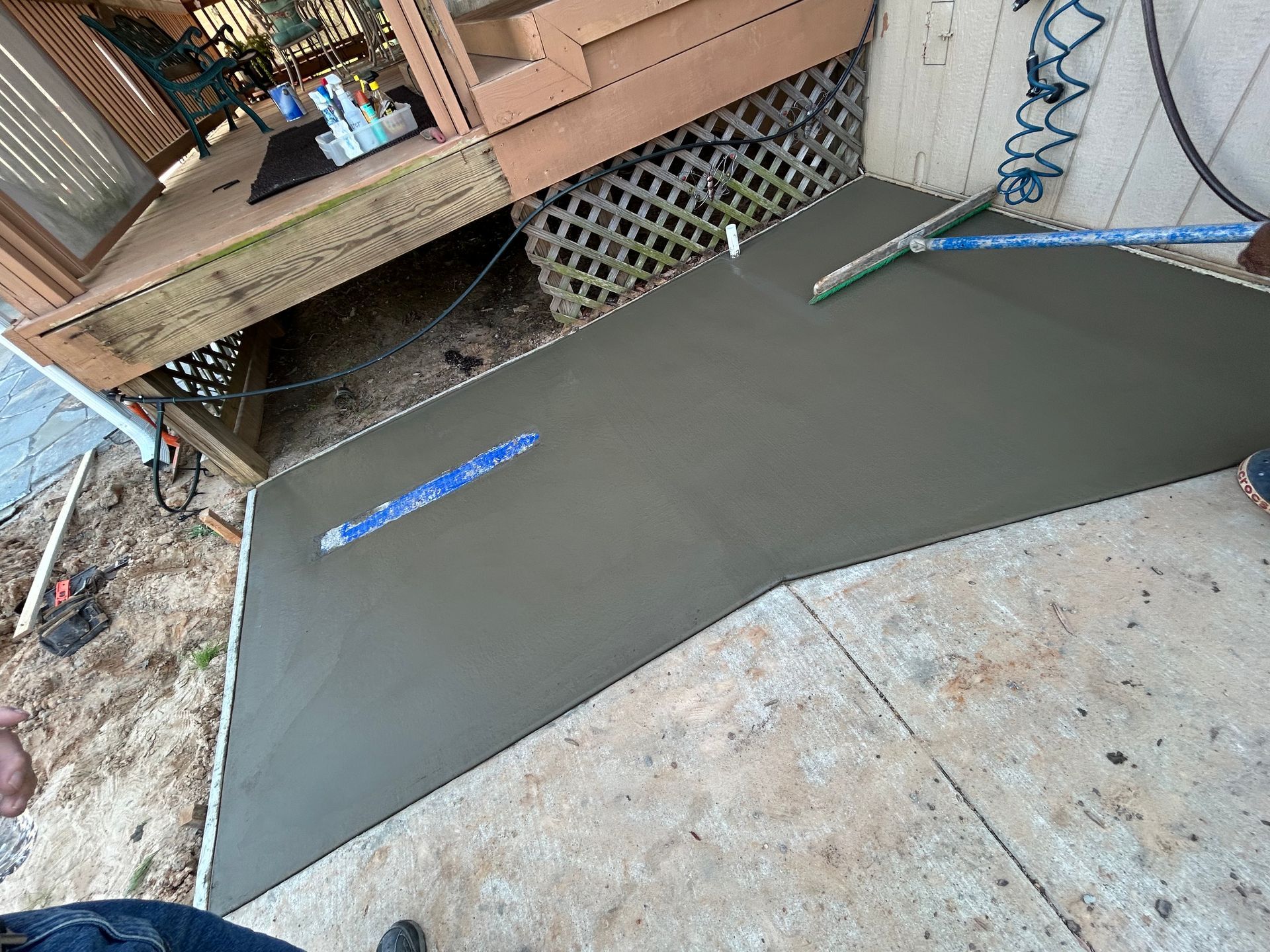 Freshly poured concrete ramp providing a smooth, level transition between a concrete patio and a raised wooden deck.