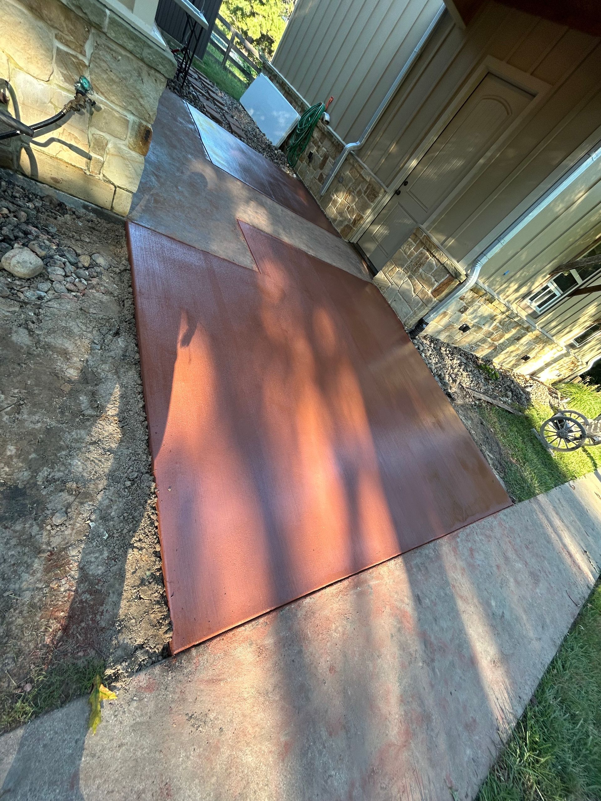 A reddish-brown rubber mat laid on a concrete patio area outside a house.