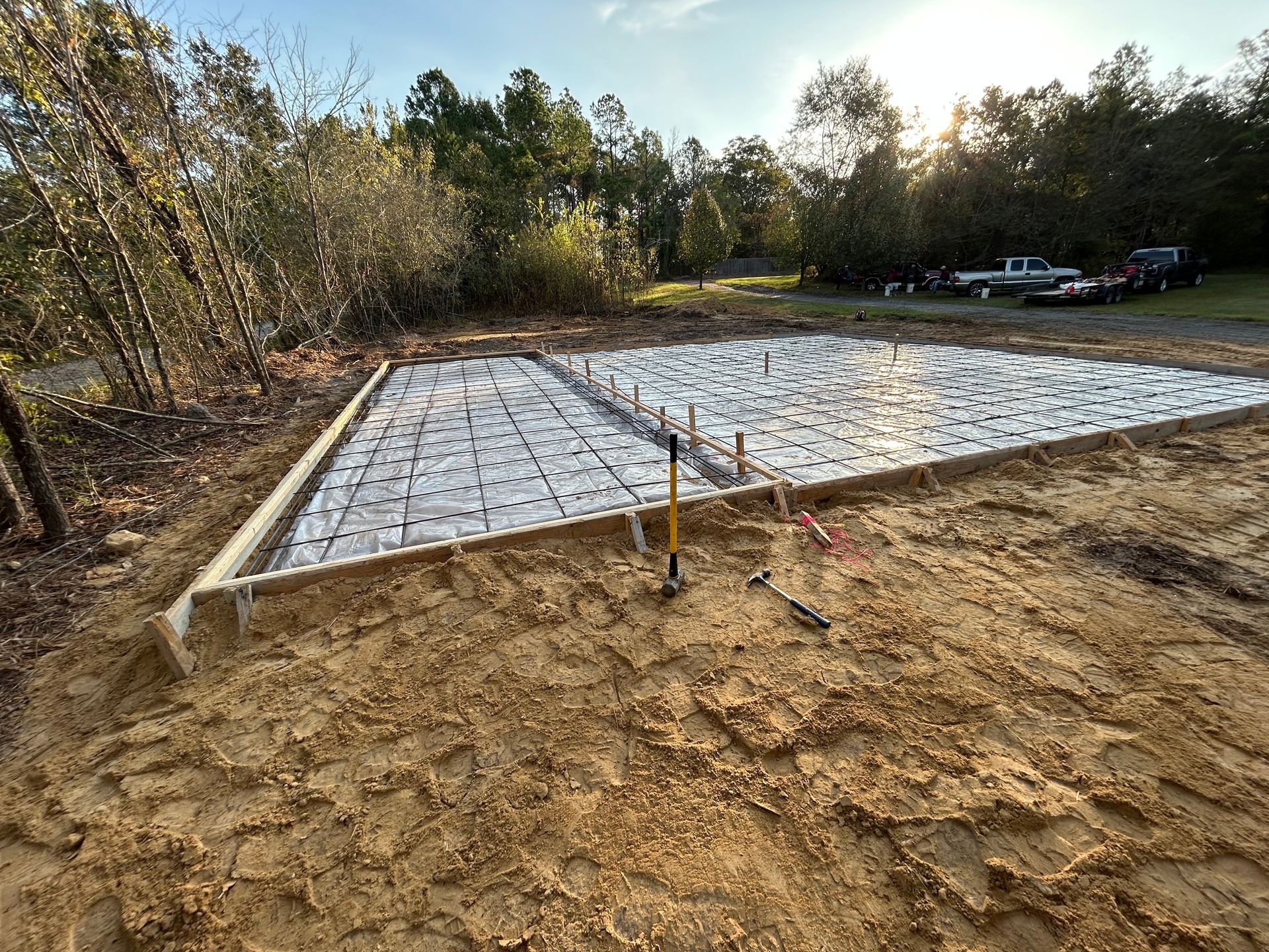 A rectangular foundation form filled with insulation panels and metal grid mesh, prepared for pouring concrete outdoors.