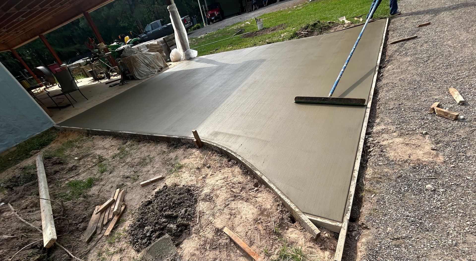 A person uses a tool to smooth wet concrete on an outdoor patio slab.