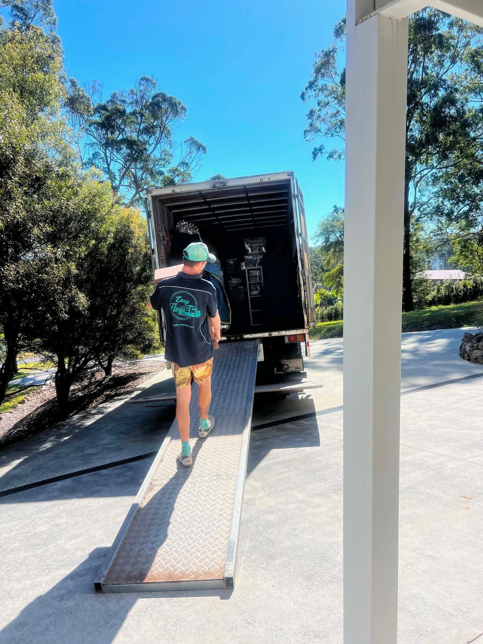 Mover walking towards a teal removal truck carrying a load — Easy Flow Removals In Wauchope, NSW