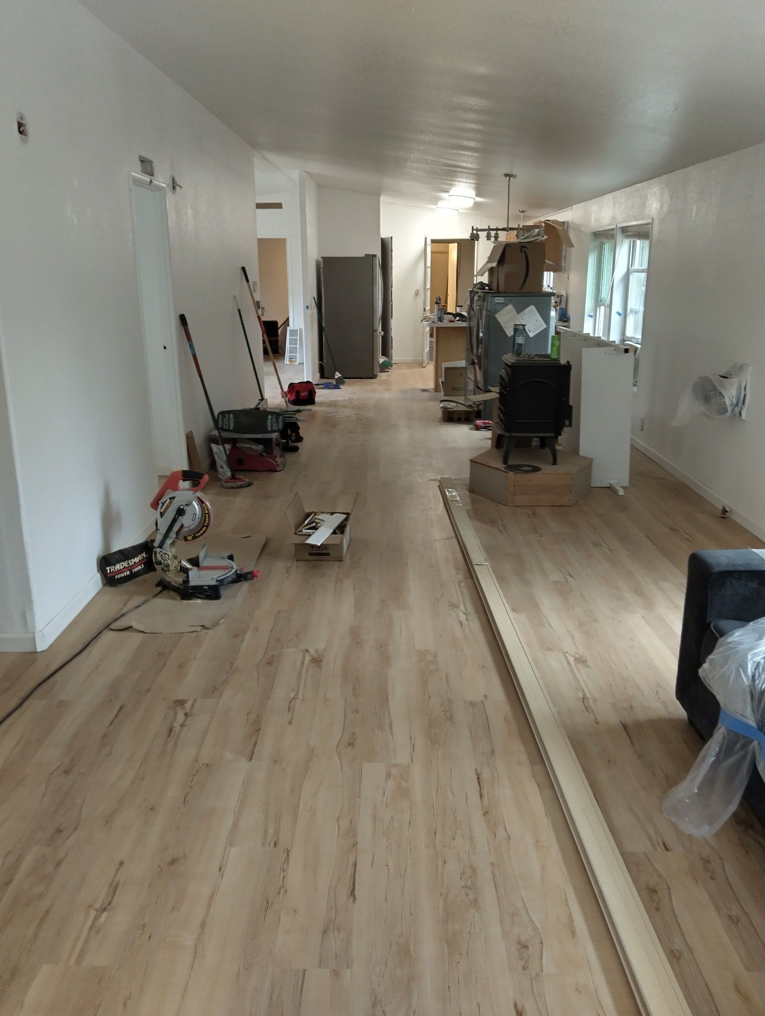 Room with light wood flooring under construction, tools and equipment scattered about.